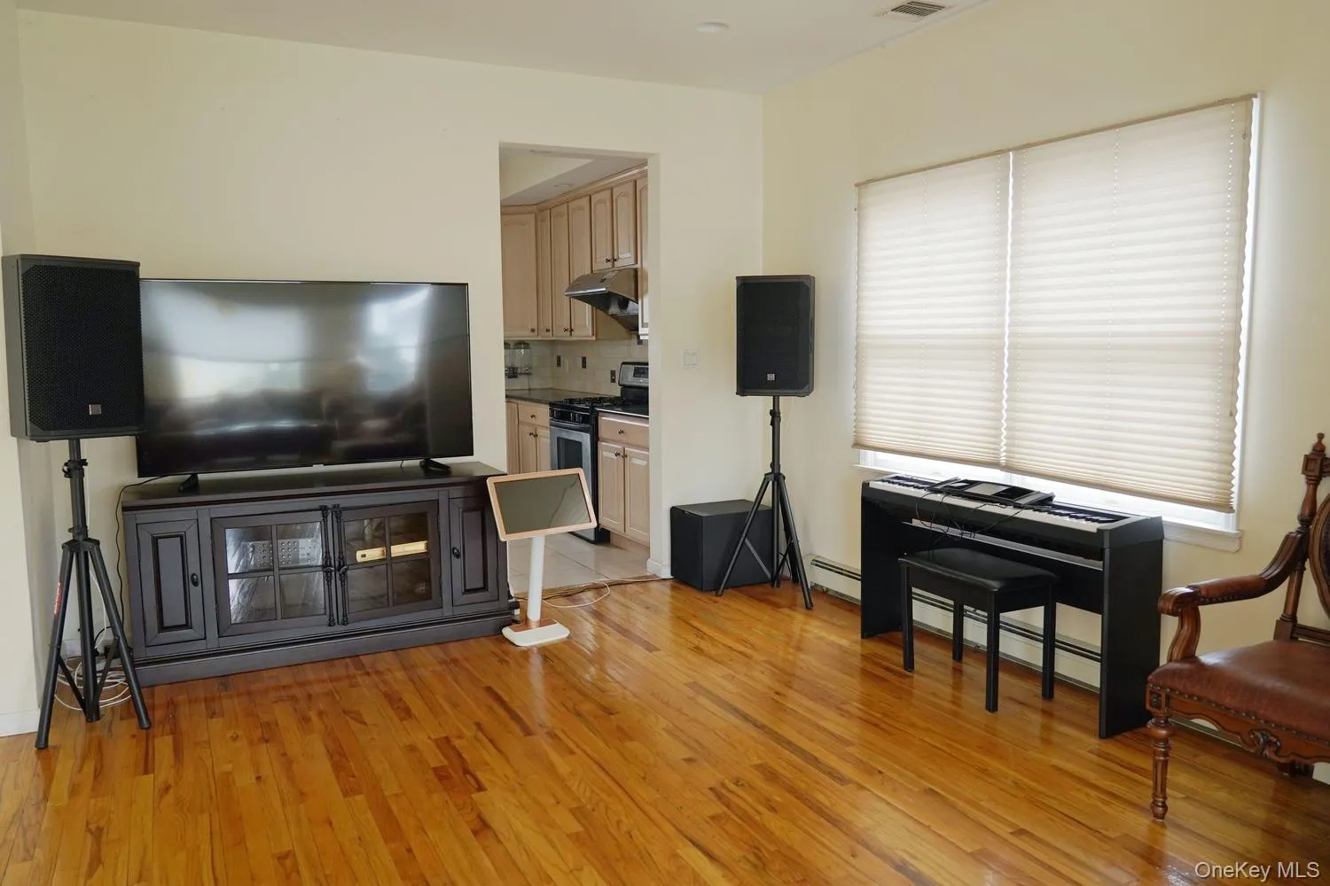 Living room featuring baseboard heating, light wood-type flooring, and visible vents Living room featuring baseboard heating, light wood-type flooring, and visible vents