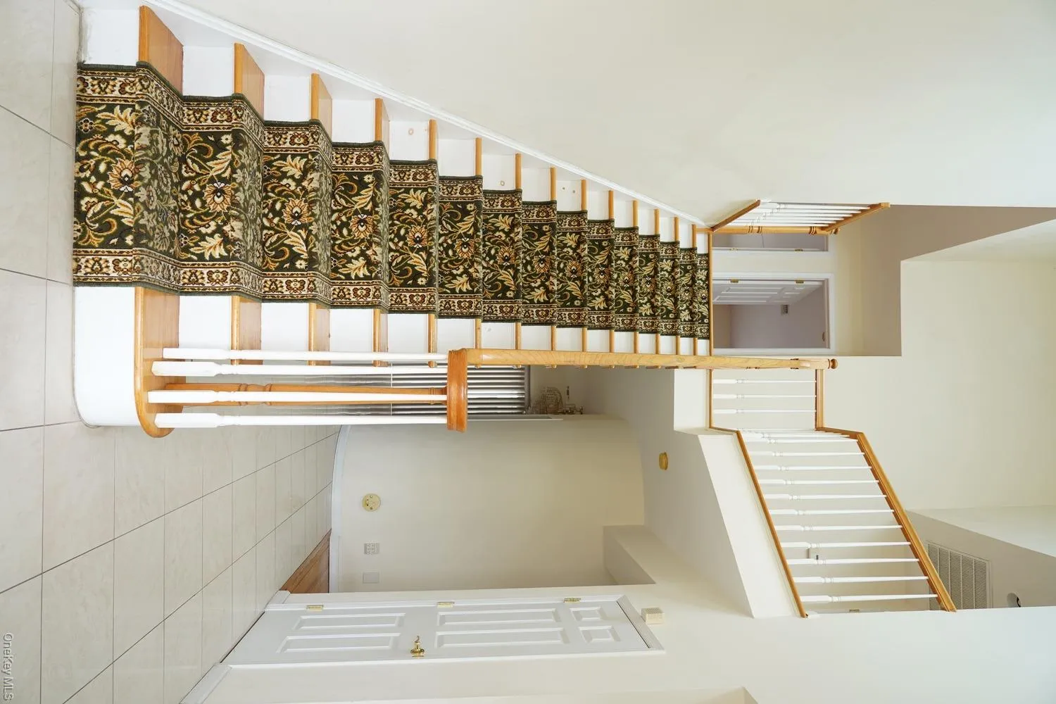 Stairs featuring tile patterned floors, a high ceiling, and baseboards Stairs featuring tile patterned floors, a high ceiling, and baseboards
