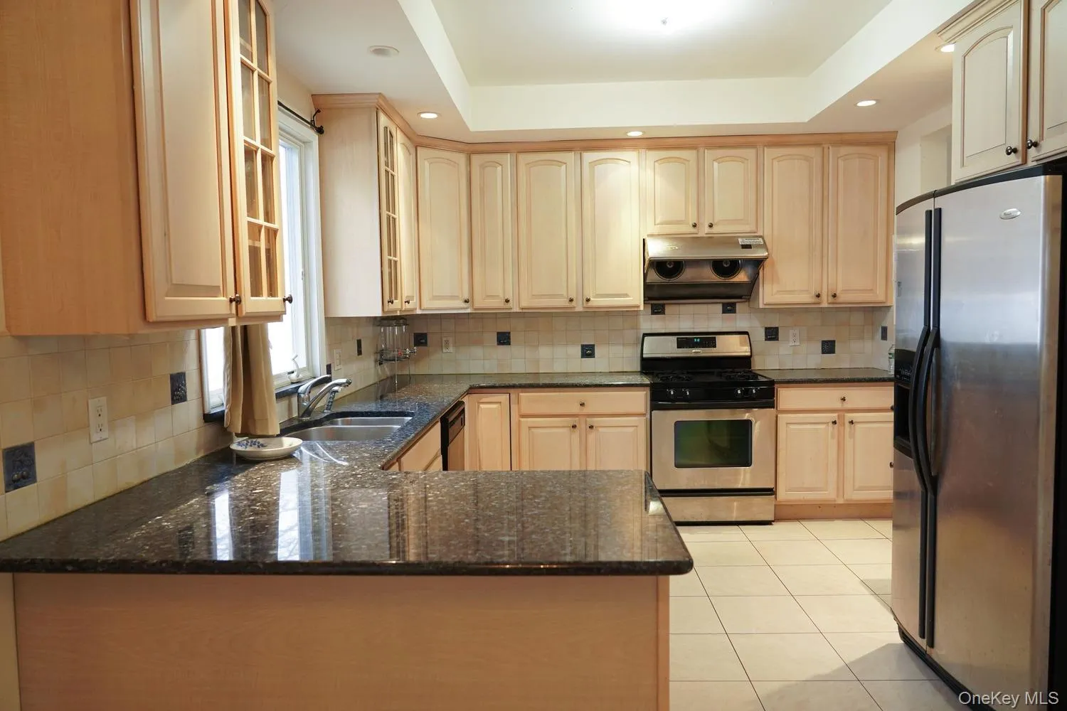 Kitchen with under cabinet range hood, a sink, light brown cabinetry, and appliances with stainless steel finishes Kitchen with under cabinet range hood, a sink, light brown cabinetry, and appliances with stainless steel finishes