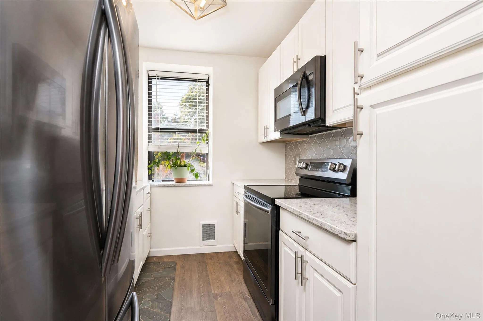 Galley kitchen with wood-finish flooring and white cabinetry Galley kitchen with wood-finish flooring and white cabinetry