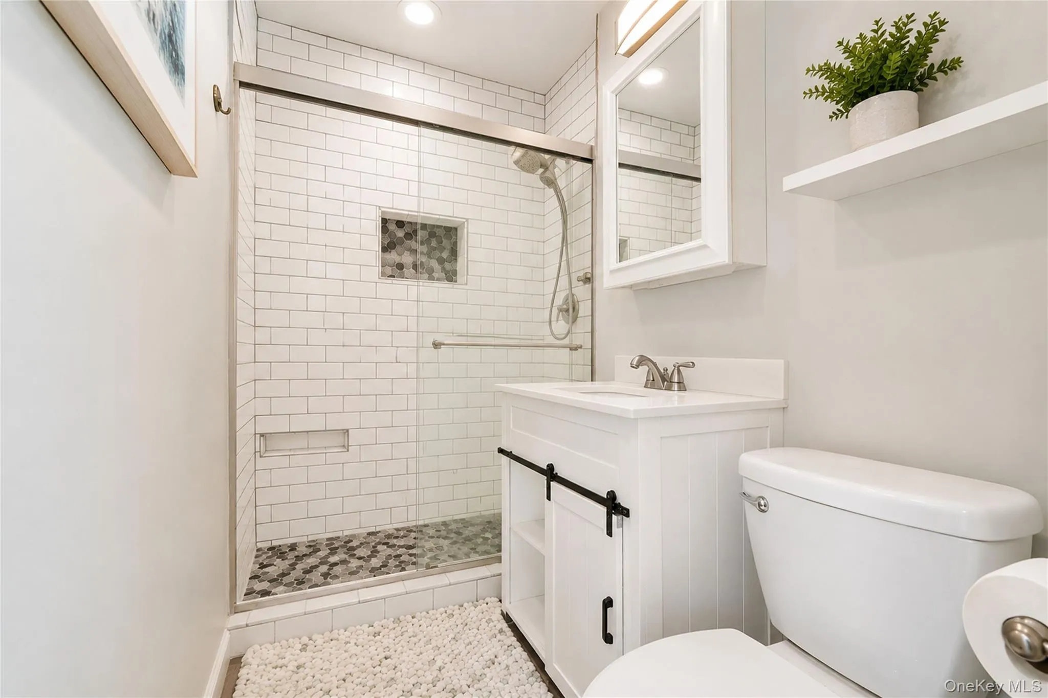 Bathroom featuring a glass-enclosed shower with subway tile surround, hexagonal tile shower floor, and a built-in shower niche Bathroom featuring a glass-enclosed shower with subway tile surround, hexagonal tile shower floor, and a built-in shower niche