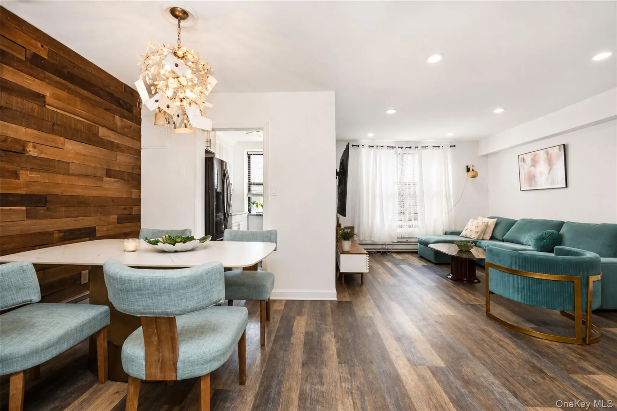 Open-concept living space featuring wood-finish flooring, recessed lighting, and a prominent wood-paneled accent wall Open-concept living space featuring wood-finish flooring, recessed lighting, and a prominent wood-paneled accent wall