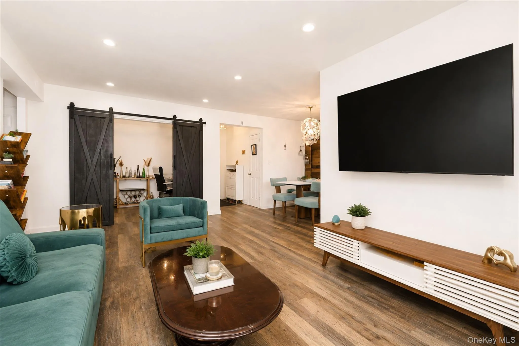 Living area featuring wood-finish flooring, recessed lighting, and a barn door entry to an additional room Living area featuring wood-finish flooring, recessed lighting, and a barn door entry to an additional room