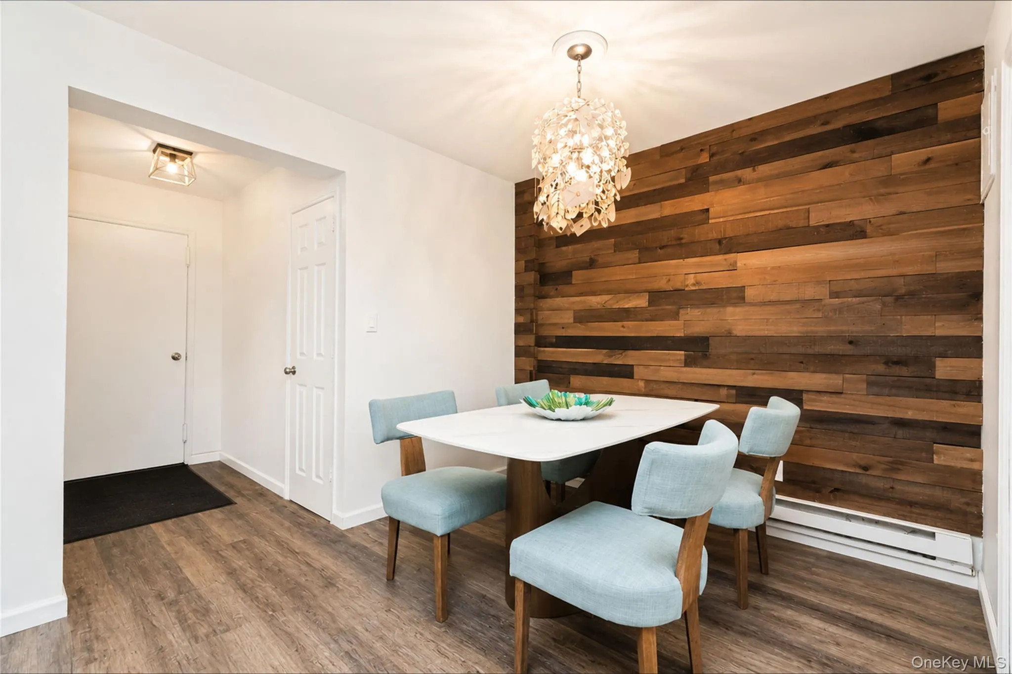 Accent wall featuring horizontal wood paneling, wood-finish flooring, and a decorative overhead lighting fixture Accent wall featuring horizontal wood paneling, wood-finish flooring, and a decorative overhead lighting fixture