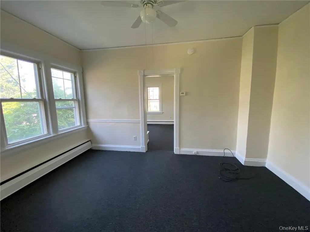 Living room with baseboard heating, new carpet flooring, and ceiling fan Living room with baseboard heating, new carpet flooring, and ceiling fan