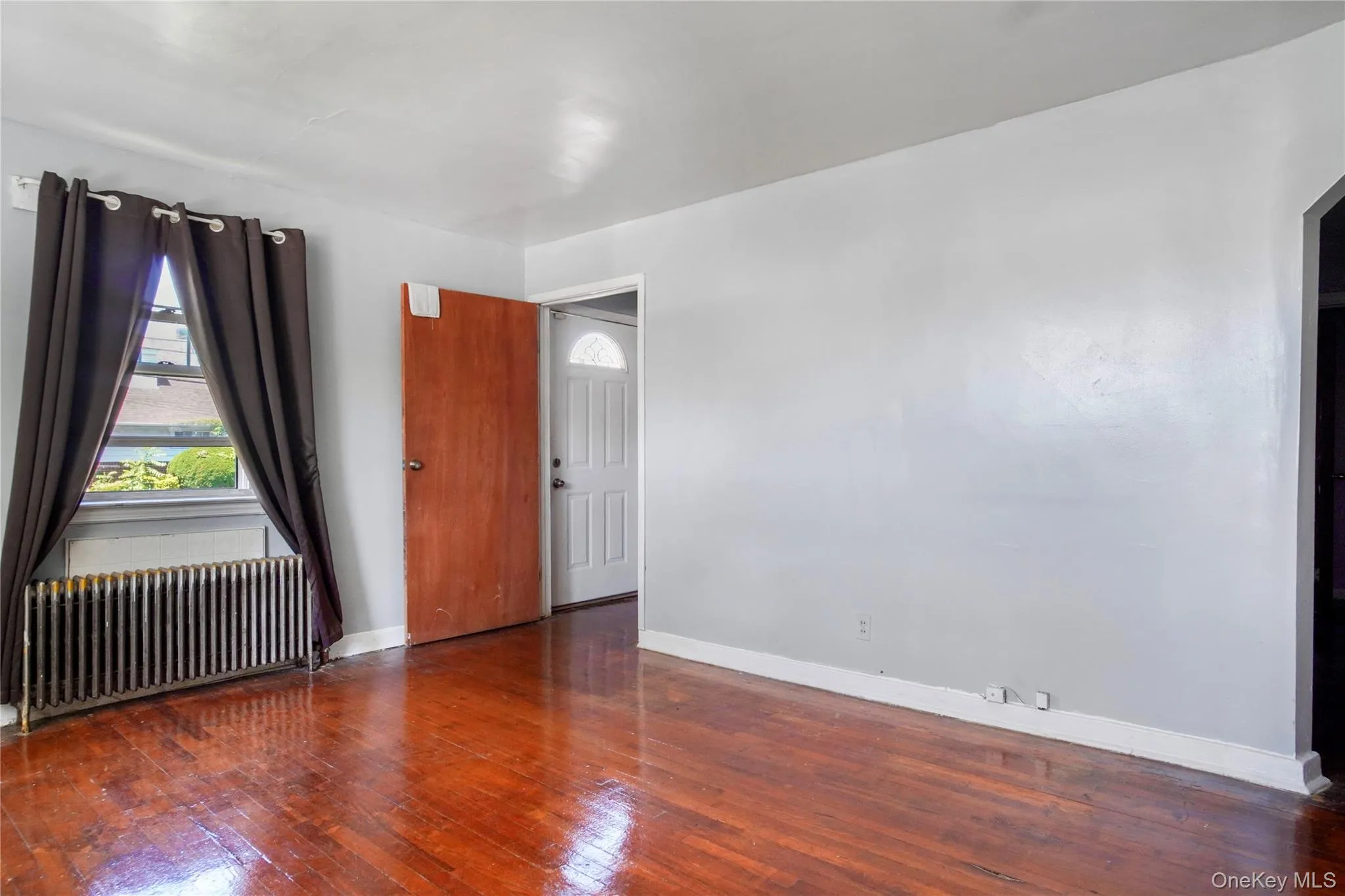 Interior space featuring wood-finish flooring, light gray walls, and white baseboards Interior space featuring wood-finish flooring, light gray walls, and white baseboards