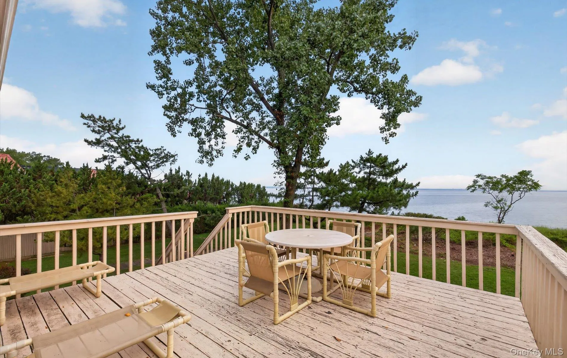 Expansive outdoor deck with a light-colored wood-finish surface and a full perimeter railing Expansive outdoor deck with a light-colored wood-finish surface and a full perimeter railing