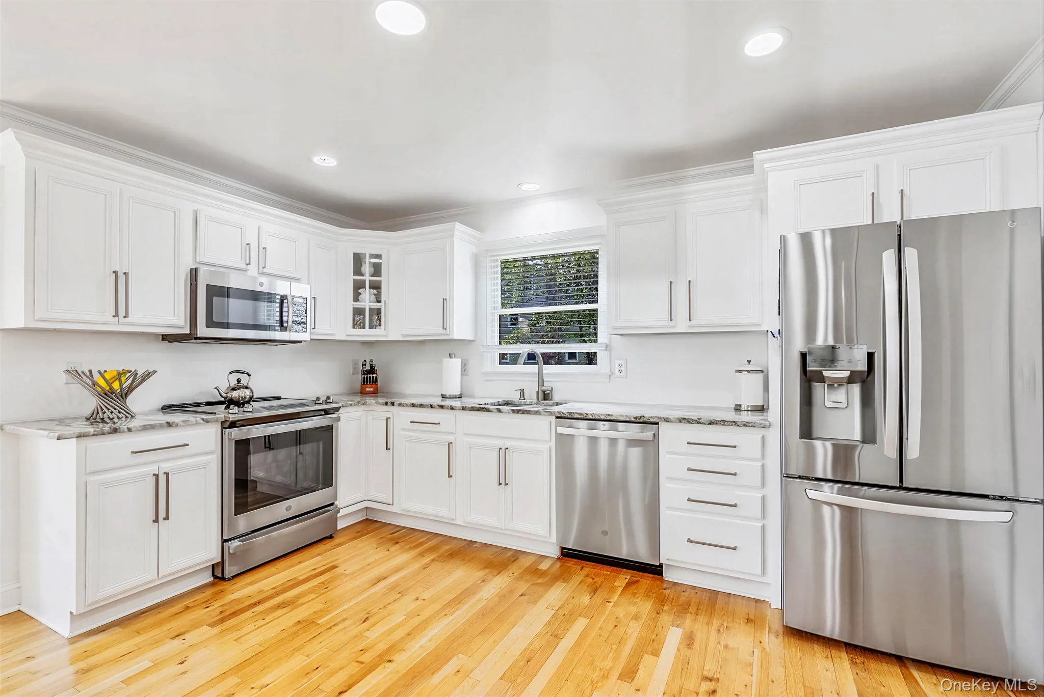 Kitchen with stainless steal appliances, white cabinets, quartz countertops, hardwood floors and recessed lighting. Kitchen with stainless steal appliances, white cabinets, quartz countertops, hardwood floors and recessed lighting.