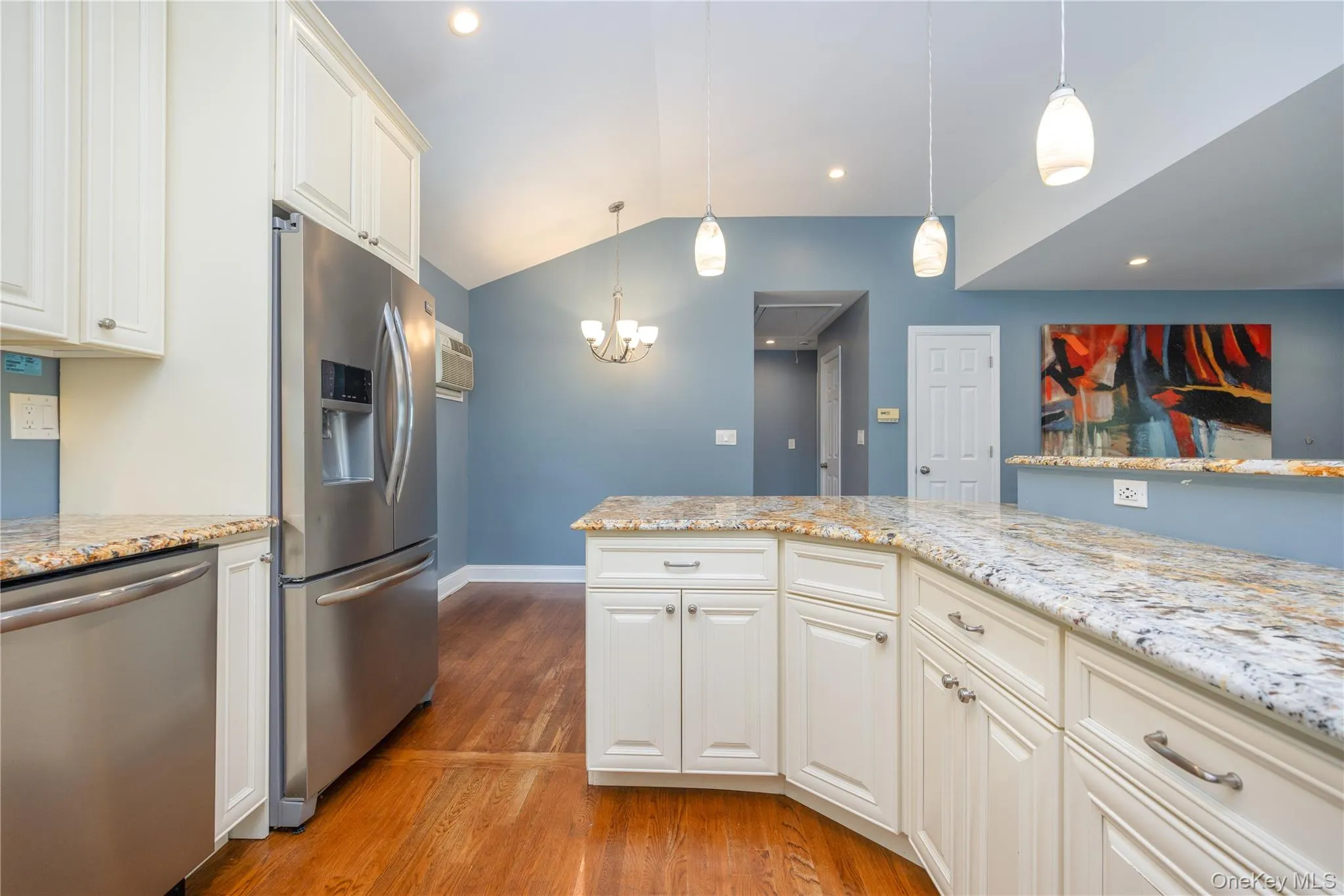 Vaulted ceiling, recessed lighting, wood-finish flooring, white cabinetry, and stainless steel appliances Vaulted ceiling, recessed lighting, wood-finish flooring, white cabinetry, and stainless steel appliances