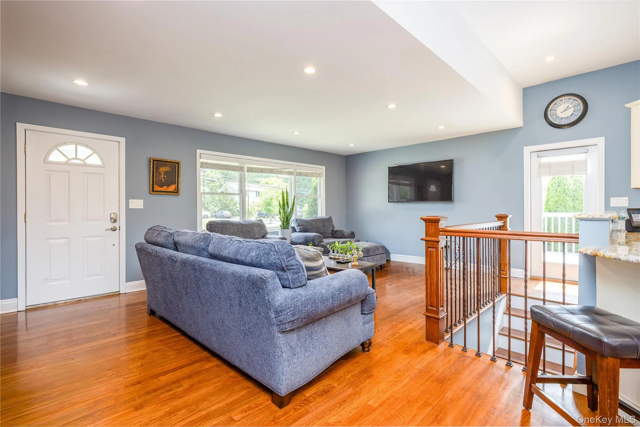 Bright, open living area showcasing gleaming wood-finish flooring throughout, recessed ceiling lighting, and soft blue-gray wall finishes Bright, open living area showcasing gleaming wood-finish flooring throughout, recessed ceiling lighting, and soft blue-gray wall finishes