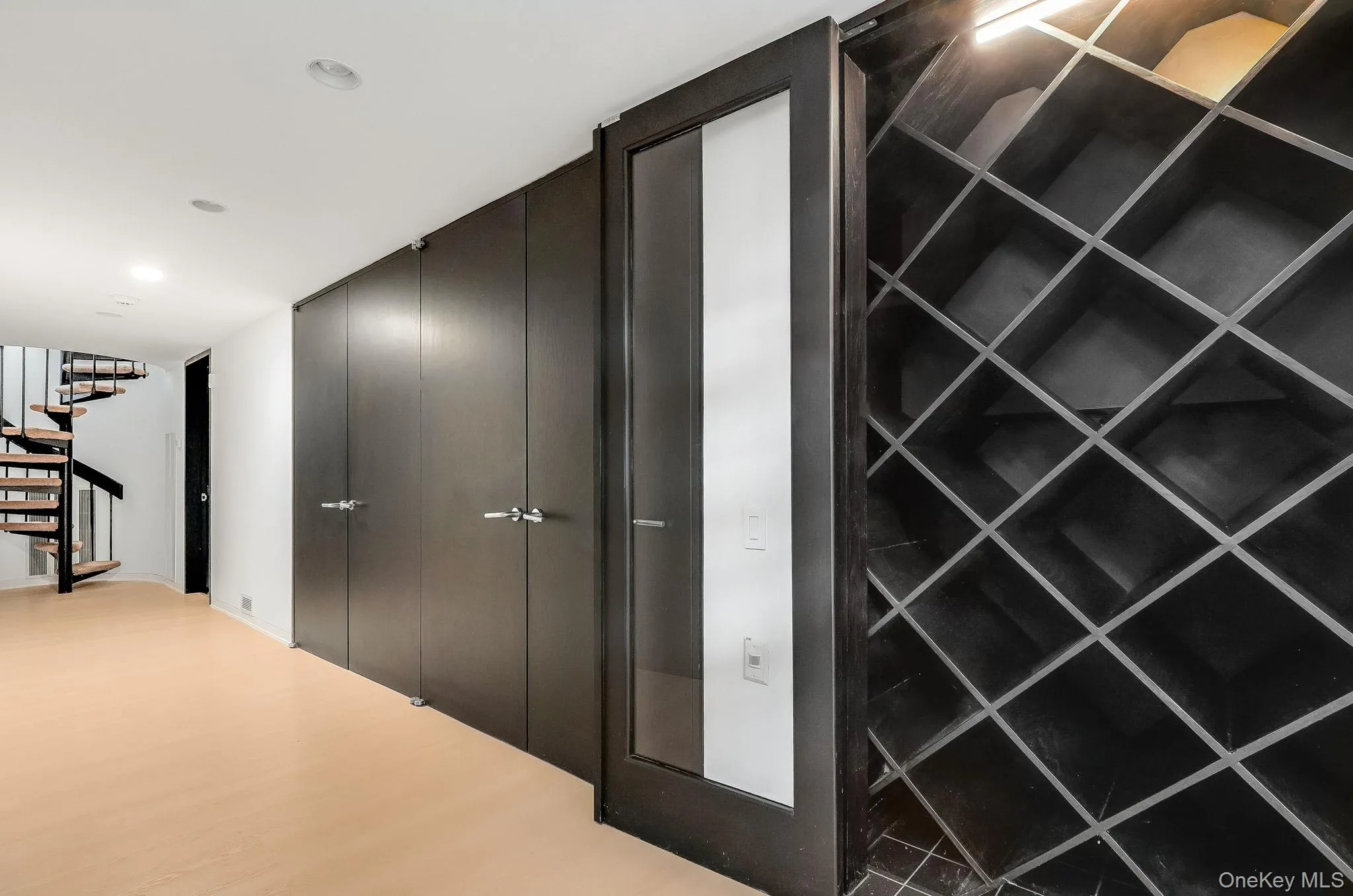 An elegant built-in wine wall featuring custom diamond-grid shelving and a modern glass-paneled accent door. An elegant built-in wine wall featuring custom diamond-grid shelving and a modern glass-paneled accent door.