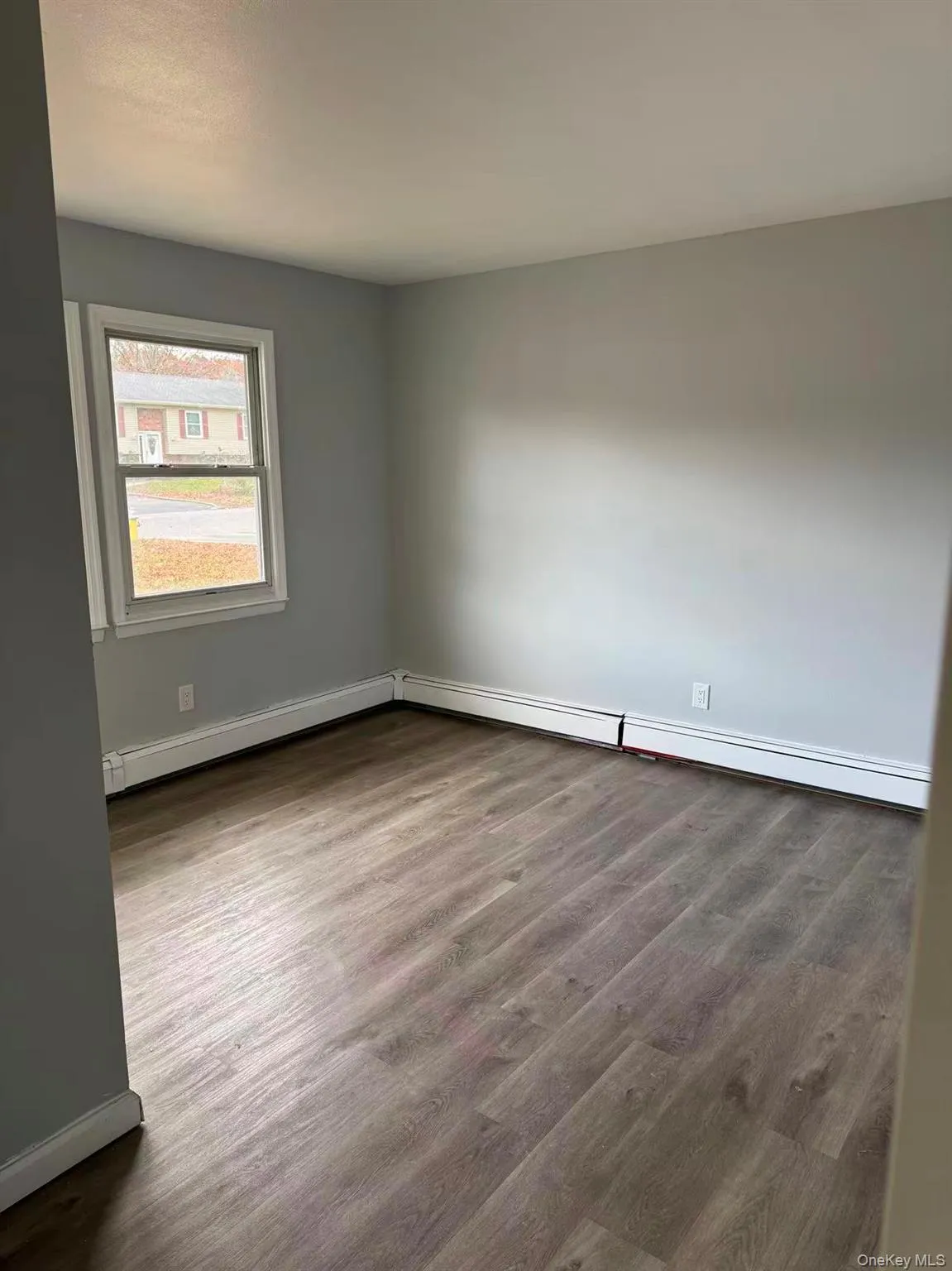 Unfurnished room featuring dark wood-type flooring and a baseboard heating unit Unfurnished room featuring dark wood-type flooring and a baseboard heating unit