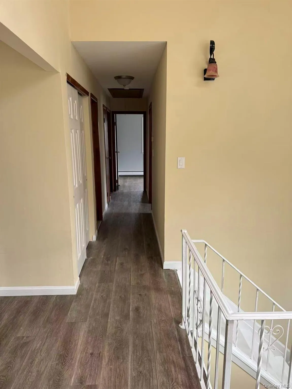Hallway with baseboards and dark wood finished floors Hallway with baseboards and dark wood finished floors