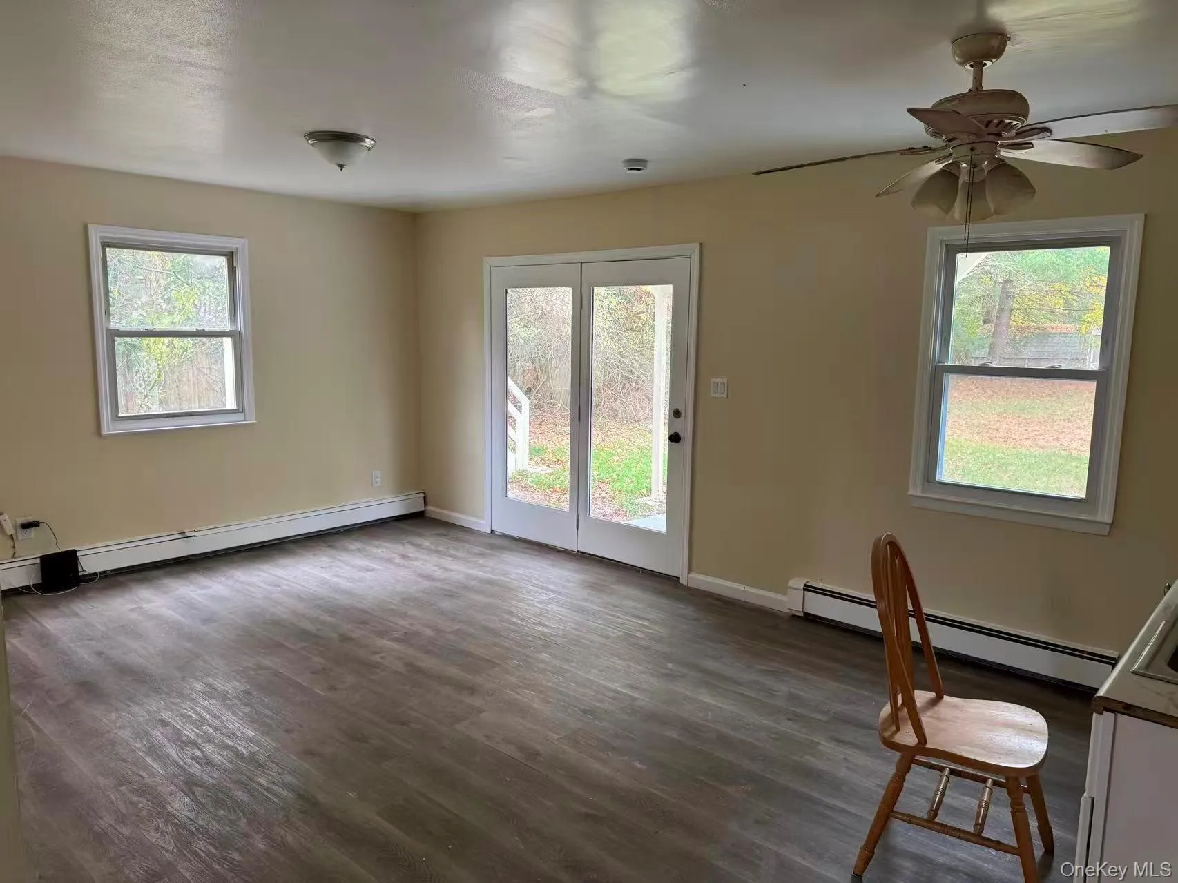 Large space at first floor for living room plus dining area. with a baseboard heating unit, dark wood finished floors, and plenty of natural light, another door access to Backyard Large space at first floor for living room plus dining area. with a baseboard heating unit, dark wood finished floors, and plenty of natural light, another door access to Backyard