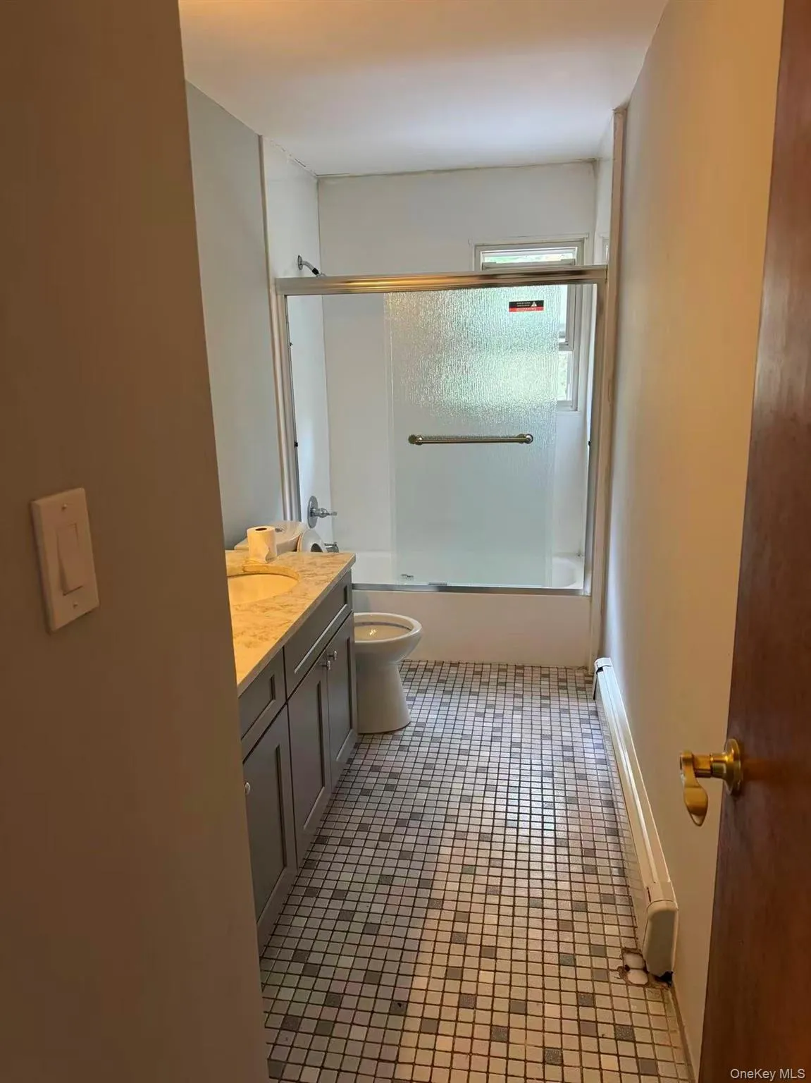 Bathroom with vanity, shower / bath combination with glass door, and light tile patterned floors Bathroom with vanity, shower / bath combination with glass door, and light tile patterned floors