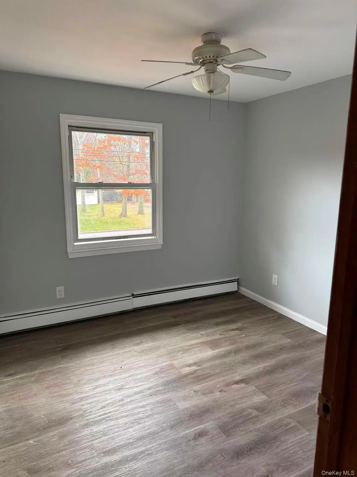 Empty room featuring a baseboard radiator, light wood-style flooring, and a ceiling fan Empty room featuring a baseboard radiator, light wood-style flooring, and a ceiling fan