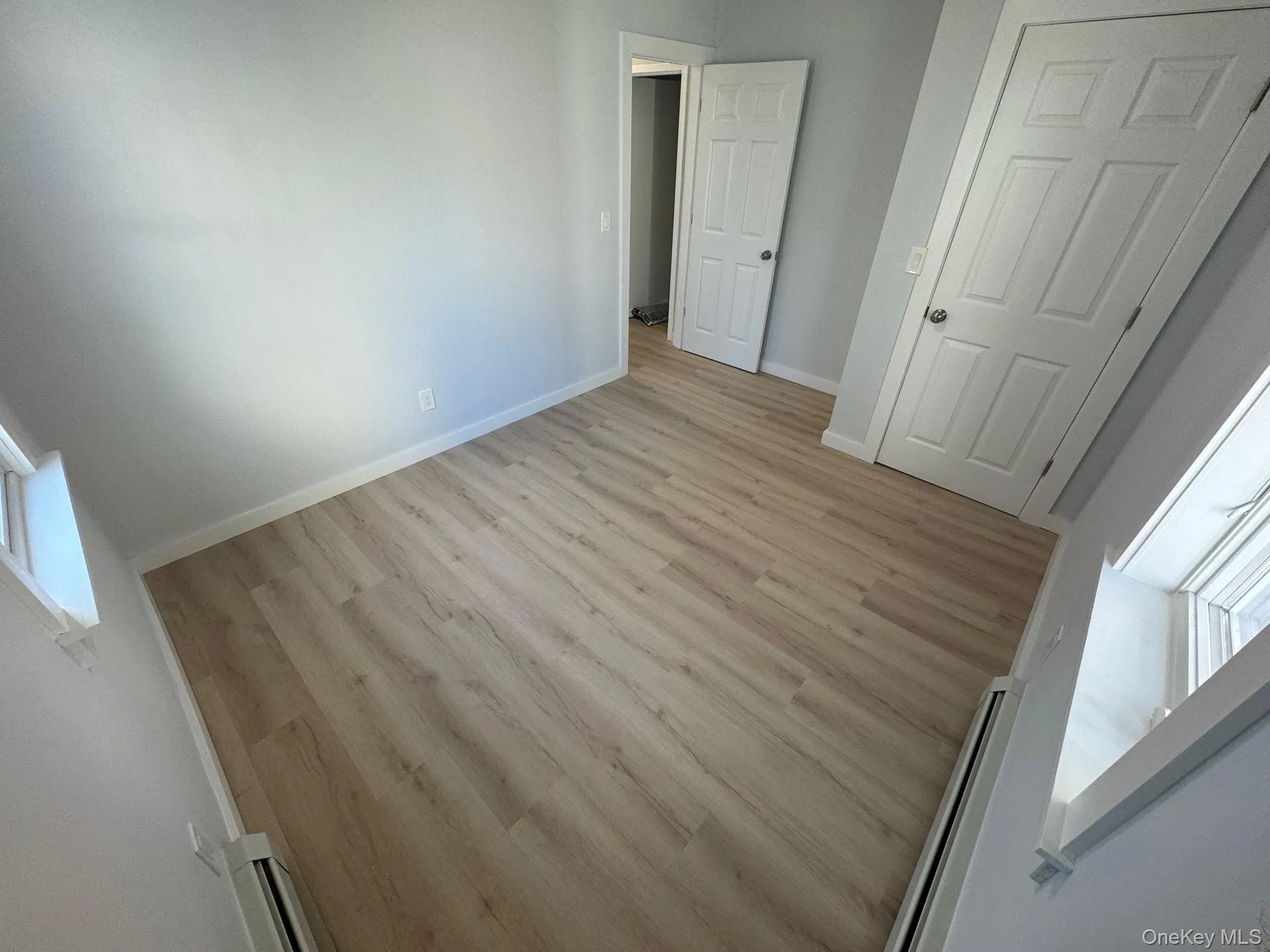 Unfurnished bedroom with light wood-type flooring, a baseboard heating unit, and baseboards Unfurnished bedroom with light wood-type flooring, a baseboard heating unit, and baseboards