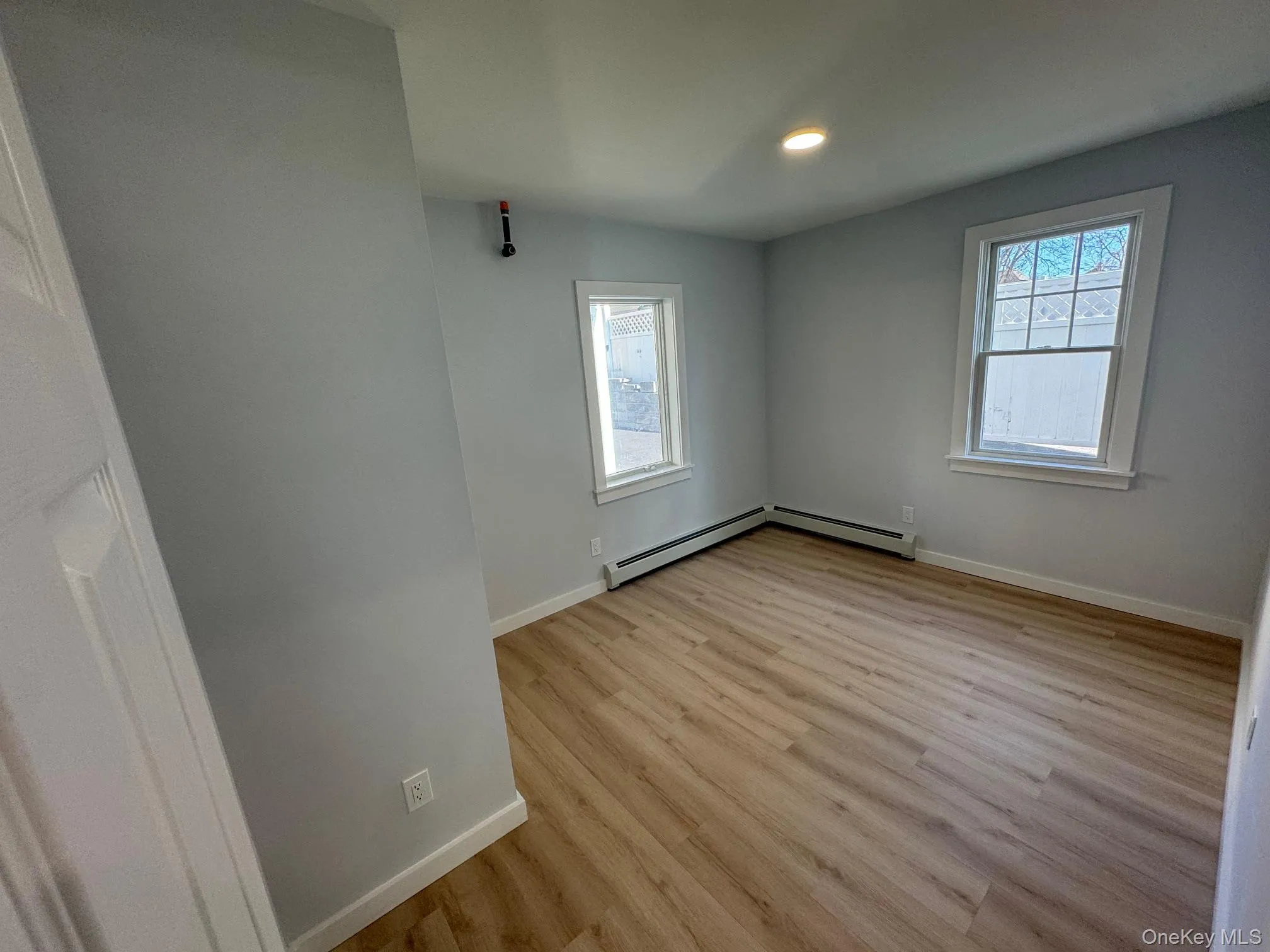 Unfurnished room featuring light wood-type flooring, a baseboard radiator, baseboards, and recessed lighting Unfurnished room featuring light wood-type flooring, a baseboard radiator, baseboards, and recessed lighting