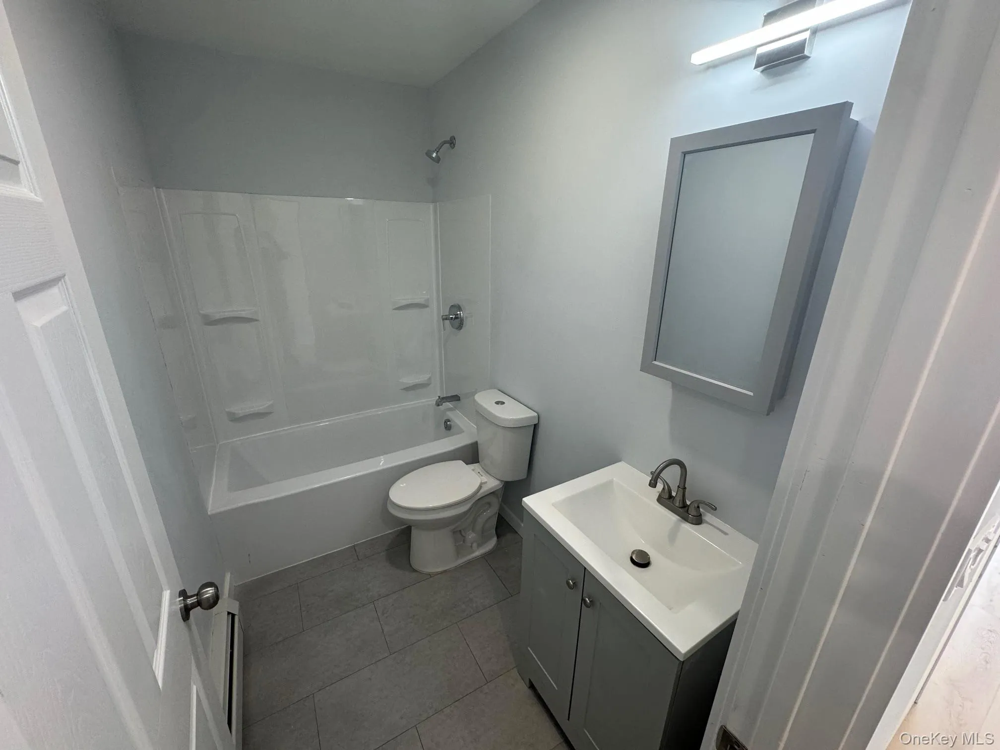 Bathroom with vanity, toilet, shower / bath combination, and tile patterned floors Bathroom with vanity, toilet, shower / bath combination, and tile patterned floors