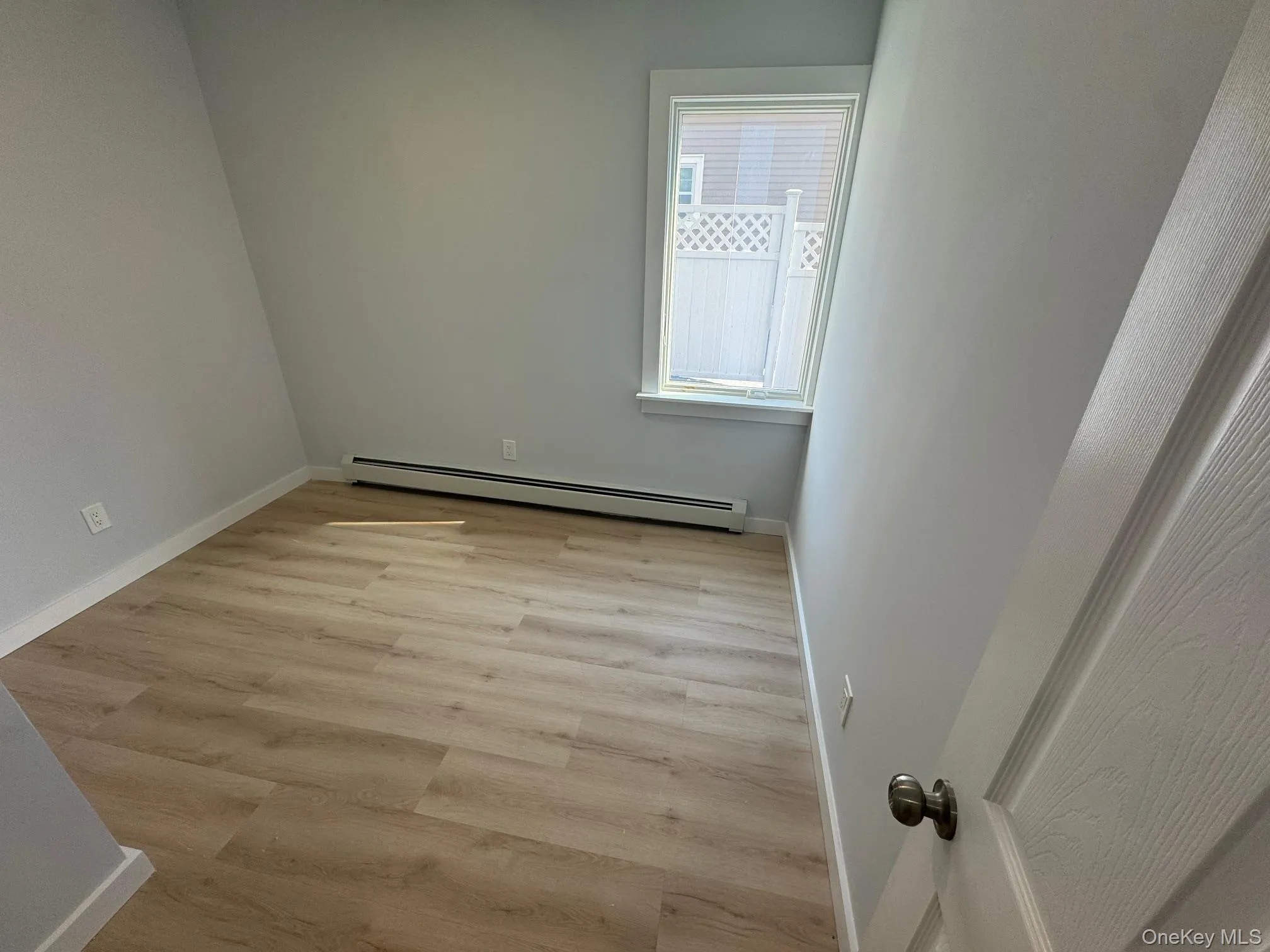 Spare room with baseboard heating, baseboards, and light wood-style floors Spare room with baseboard heating, baseboards, and light wood-style floors