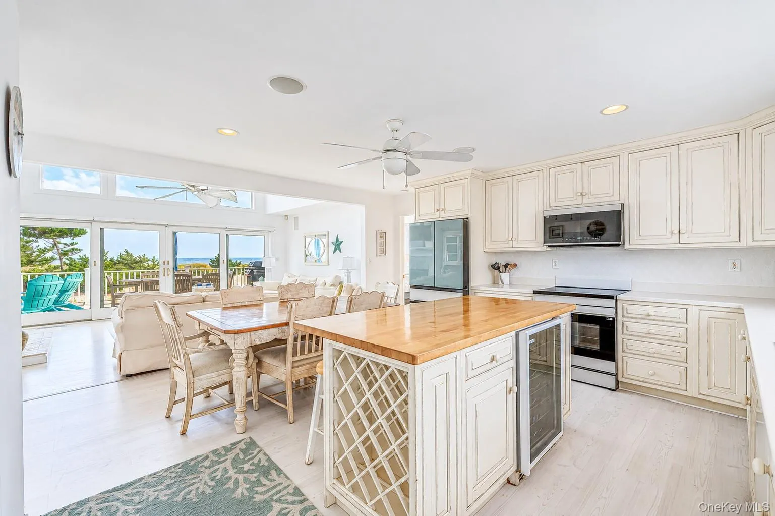 Open-concept kitchen featuring white cabinetry, light wood-finish flooring, a kitchen island with a wood countertop and integrated wine storage, featuring brand new appliances