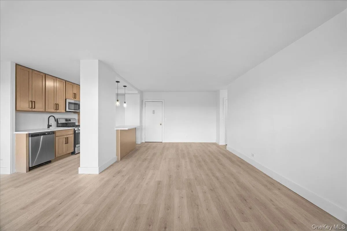 Open concept living space with light-tone vinyl flooring, white walls Open concept living space with light-tone vinyl flooring, white walls