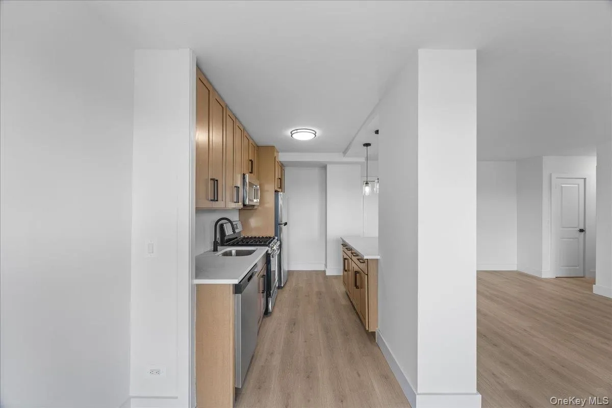 Modern kitchen featuring light wood-finish cabinetry, stainless steel appliances, and a black-finish faucet Modern kitchen featuring light wood-finish cabinetry, stainless steel appliances, and a black-finish faucet