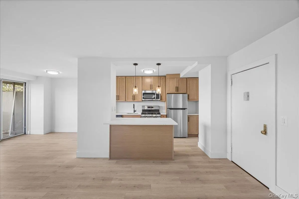 Kitchen featuring wood-finish cabinetry, stainless steel appliances, and a peninsula with countertop seating Kitchen featuring wood-finish cabinetry, stainless steel appliances, and a peninsula with countertop seating
