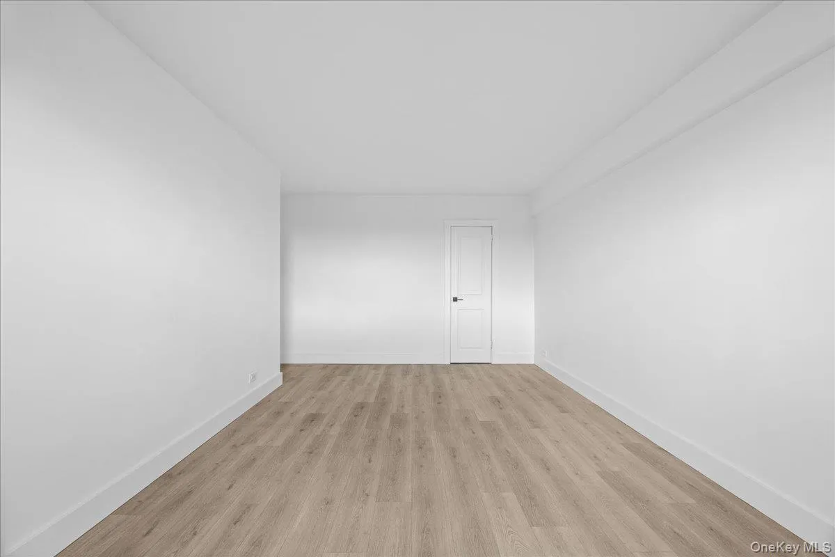 Bright interior space featuring a light vinyl, white walls, and a white interior door with dark hardware Bright interior space featuring a light vinyl, white walls, and a white interior door with dark hardware