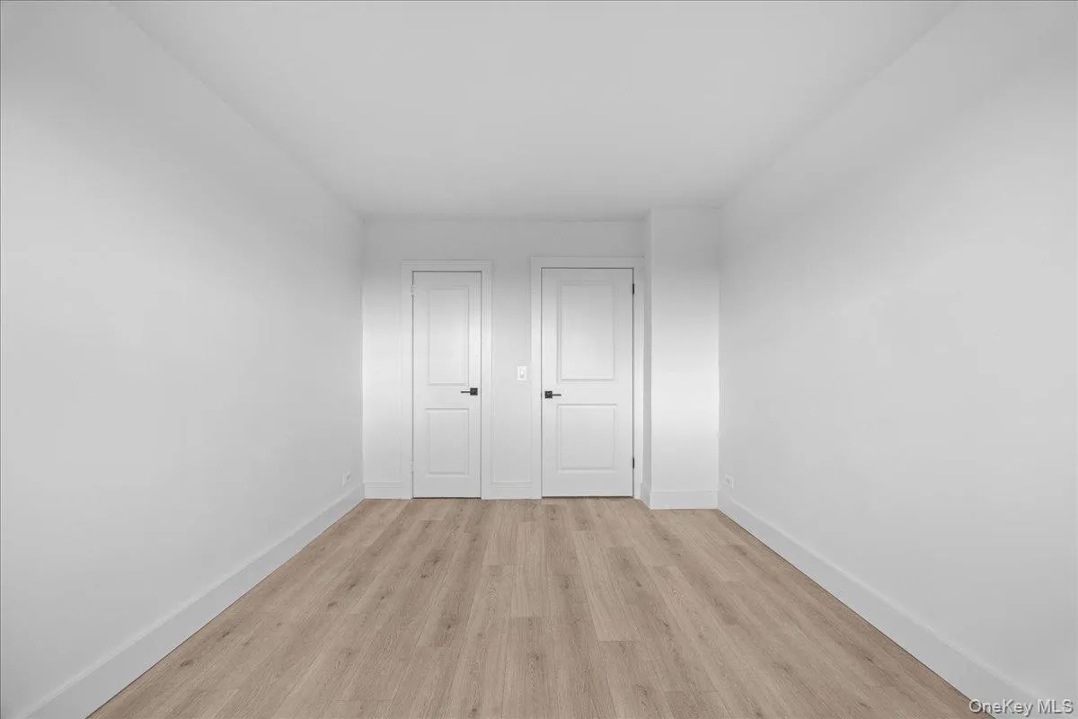 Bright interior space featuring a light vinyl, white walls, and a white interior door with dark hardware Bright interior space featuring a light vinyl, white walls, and a white interior door with dark hardware