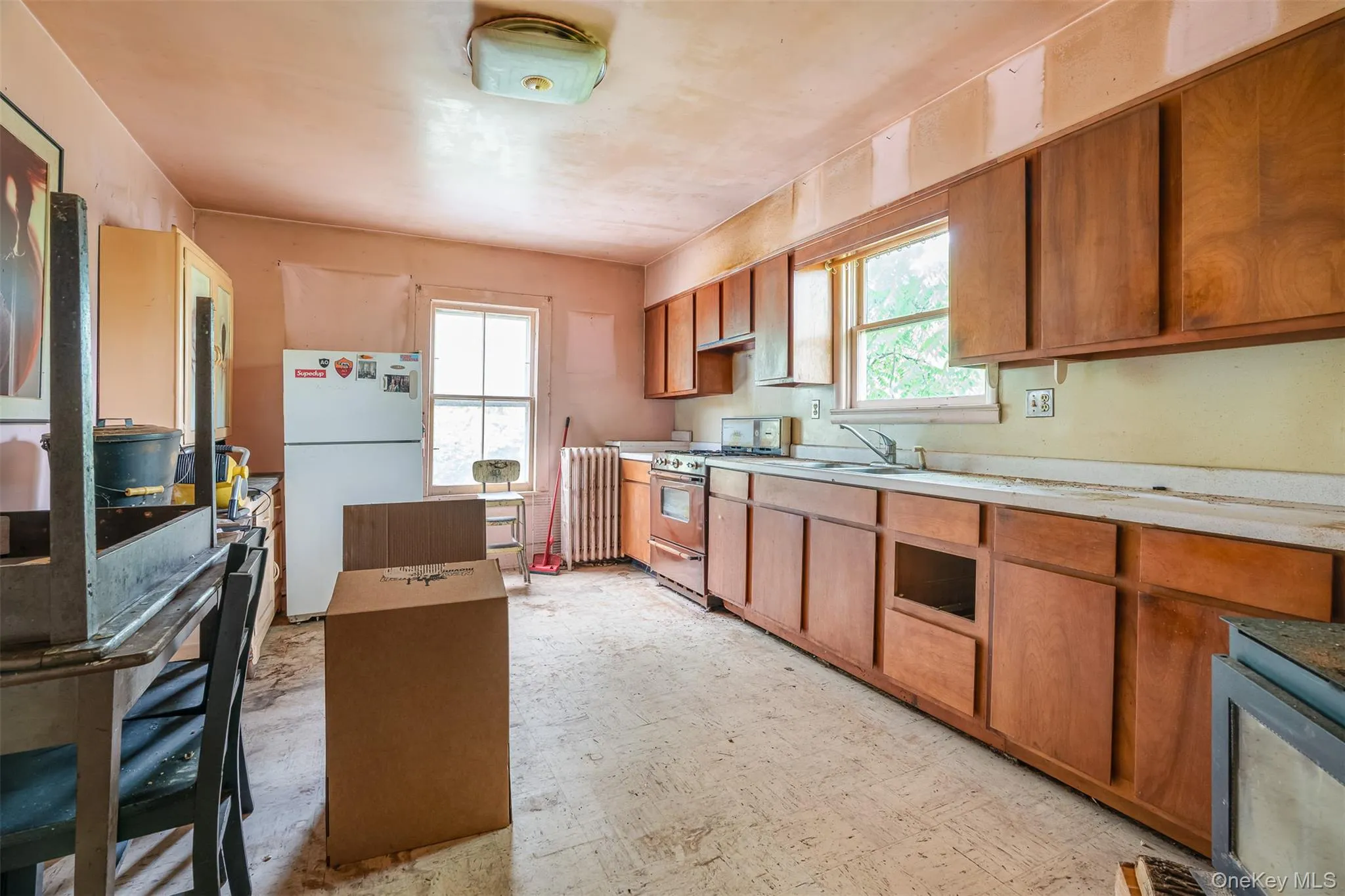 Kitchen featuring freestanding refrigerator, range with gas cooktop, light countertops, and brown cabinets Kitchen featuring freestanding refrigerator, range with gas cooktop, light countertops, and brown cabinets