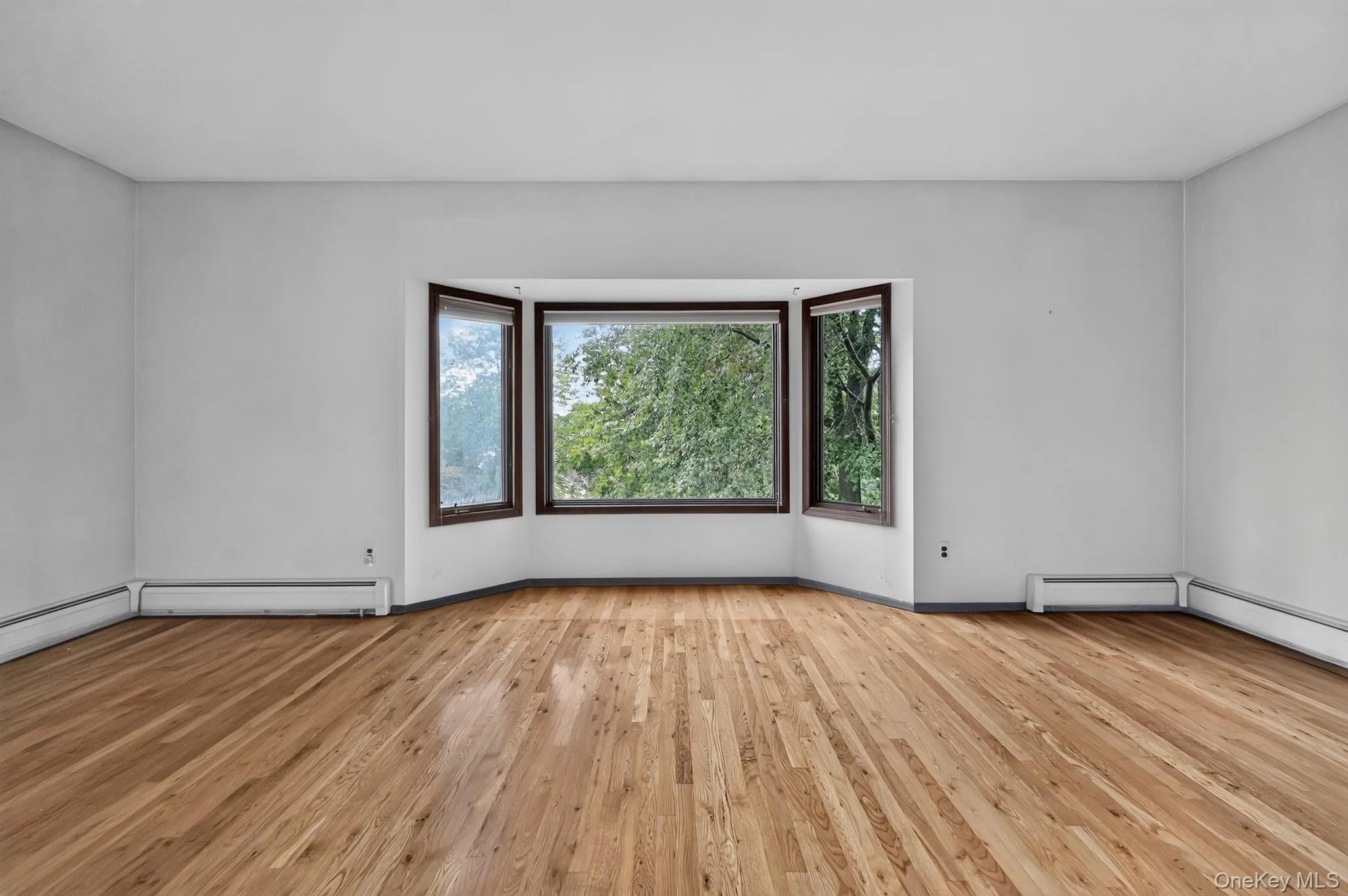 Hardwood flooring throughout, a bay window with trim, and light-toned walls Hardwood flooring throughout, a bay window with trim, and light-toned walls