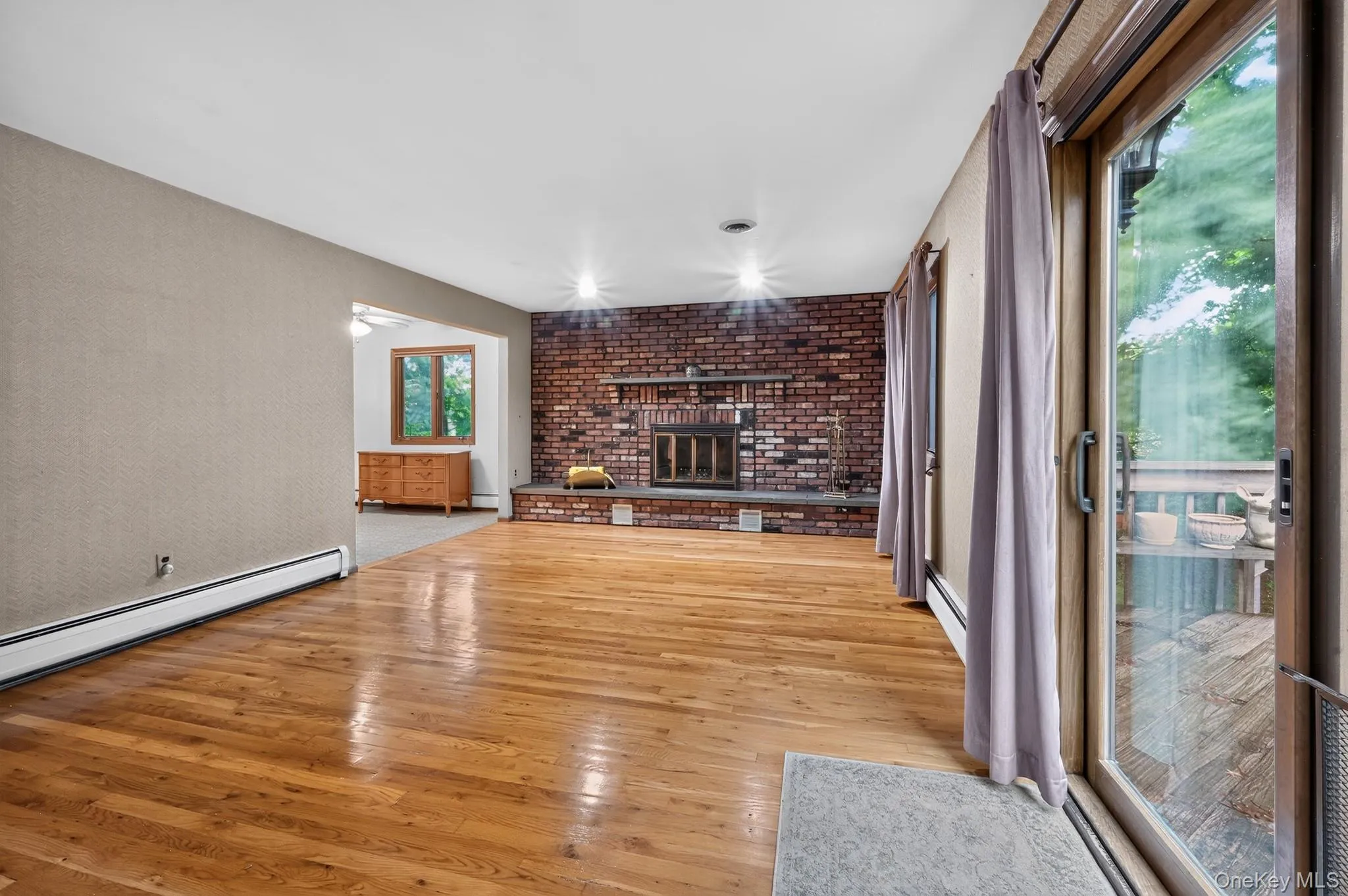 A warm and inviting family room featuring a classic full-wall brick fireplace equipped with built-in ventilator fans, with sliding glass doors leading out to a large wood deck. A warm and inviting family room featuring a classic full-wall brick fireplace equipped with built-in ventilator fans, with sliding glass doors leading out to a large wood deck.
