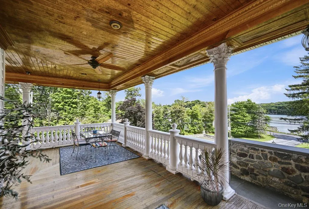 Covered porch with a wood-plank ceiling, ceiling fan, decorative balusters, and ornate columns Covered porch with a wood-plank ceiling, ceiling fan, decorative balusters, and ornate columns