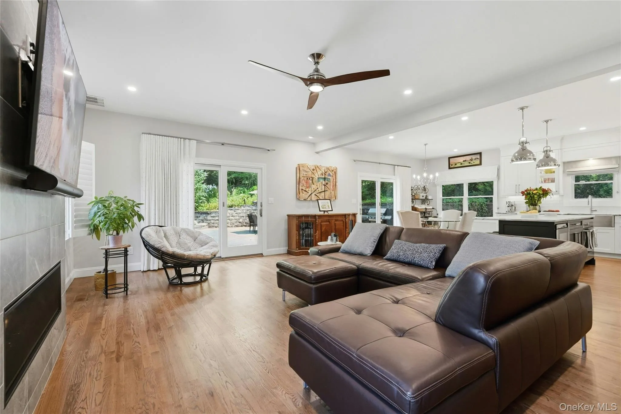Open-concept living space featuring hardwood flooring, and floor-to-ceiling windows with natural light Open-concept living space featuring hardwood flooring, and floor-to-ceiling windows with natural light