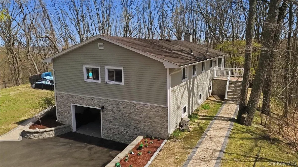Two-story siding exterior with stone-finish lower level, attached garage, and a raised deck with stairs Two-story siding exterior with stone-finish lower level, attached garage, and a raised deck with stairs
