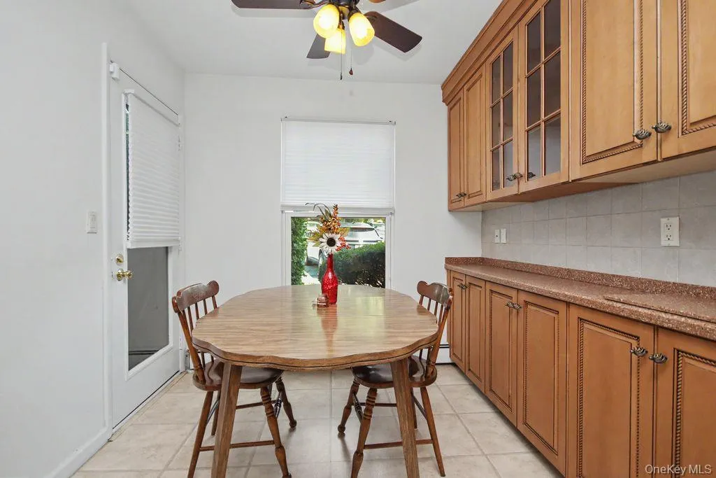 White walls, wood-finish cabinetry, tile flooring, and a ceiling fan with integrated lighting White walls, wood-finish cabinetry, tile flooring, and a ceiling fan with integrated lighting