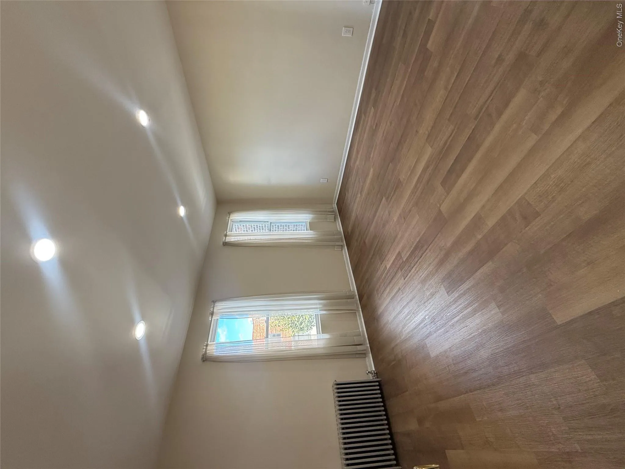 Empty room featuring radiator heating unit, recessed lighting, and wood finished floors Empty room featuring radiator heating unit, recessed lighting, and wood finished floors