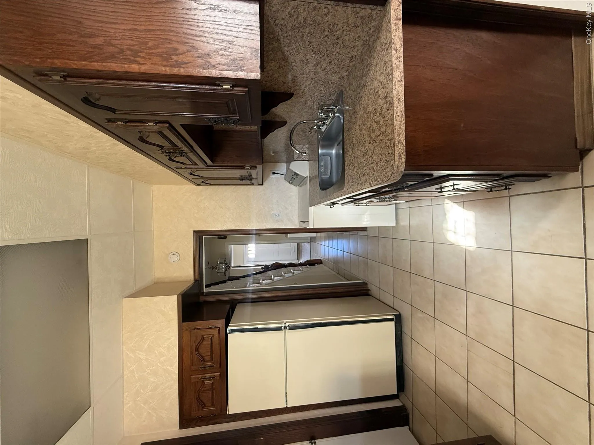 Kitchen featuring refrigerator, dark brown cabinets, light tile patterned flooring, range, and decorative backsplash Kitchen featuring refrigerator, dark brown cabinets, light tile patterned flooring, range, and decorative backsplash