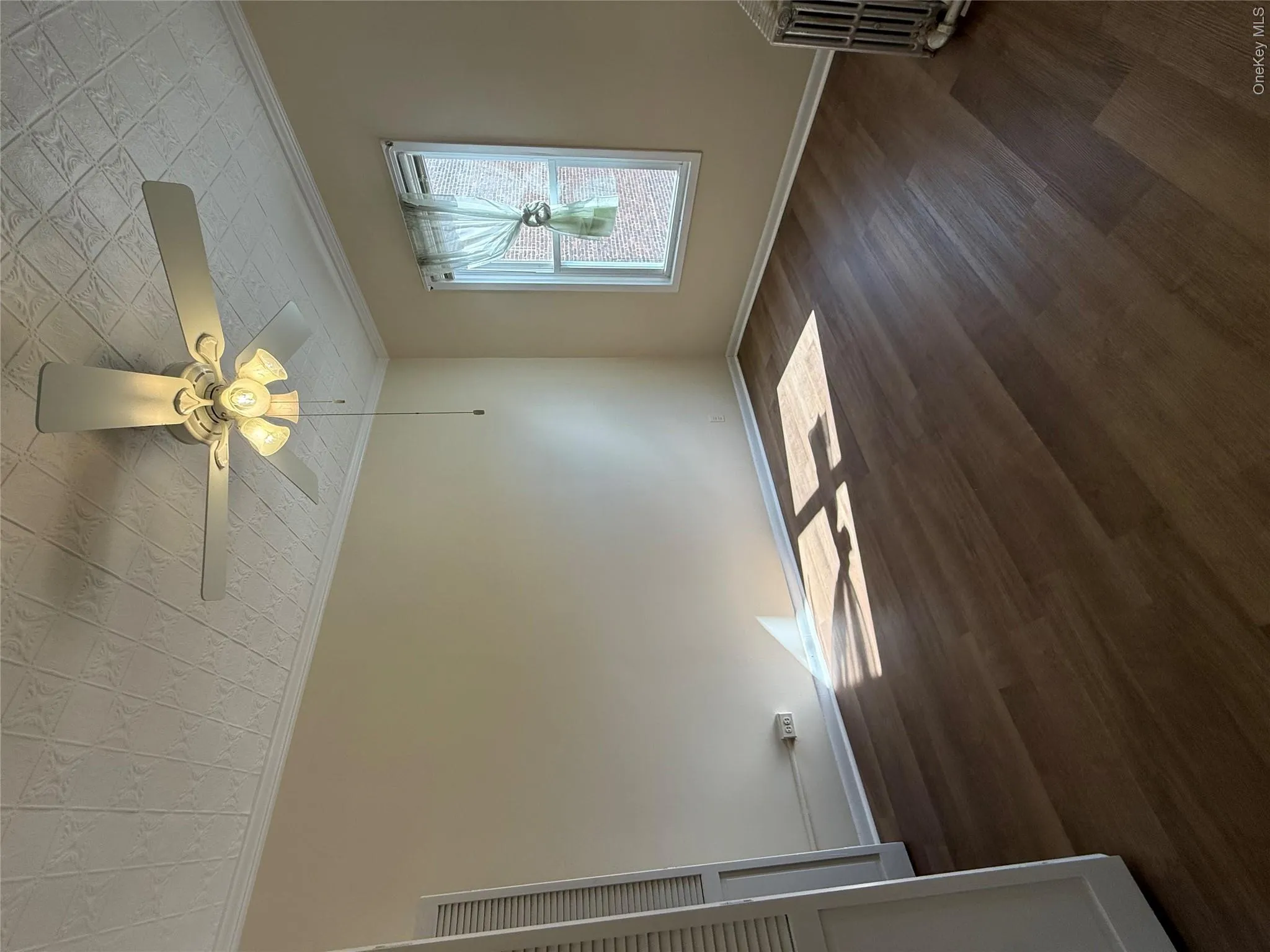 Unfurnished room featuring dark wood-style floors, an ornate ceiling, crown molding, radiator, and ceiling fan Unfurnished room featuring dark wood-style floors, an ornate ceiling, crown molding, radiator, and ceiling fan