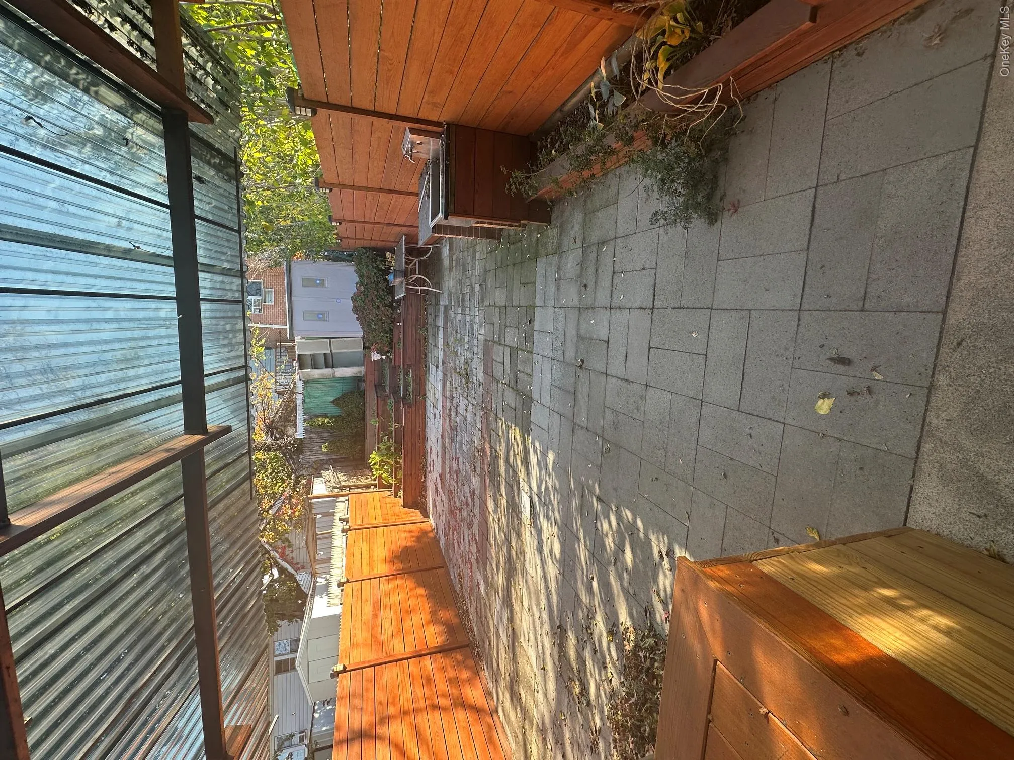 Covered patio with clear corrugated roofing, paver patio, wood fencing, and built-in wood planters Covered patio with clear corrugated roofing, paver patio, wood fencing, and built-in wood planters