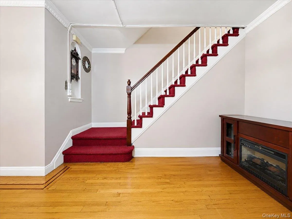 Hardwood flooring with decorative inlay, built-in display niche, fireplace unit, staircase with wood handrail, and crown molding Hardwood flooring with decorative inlay, built-in display niche, fireplace unit, staircase with wood handrail, and crown molding