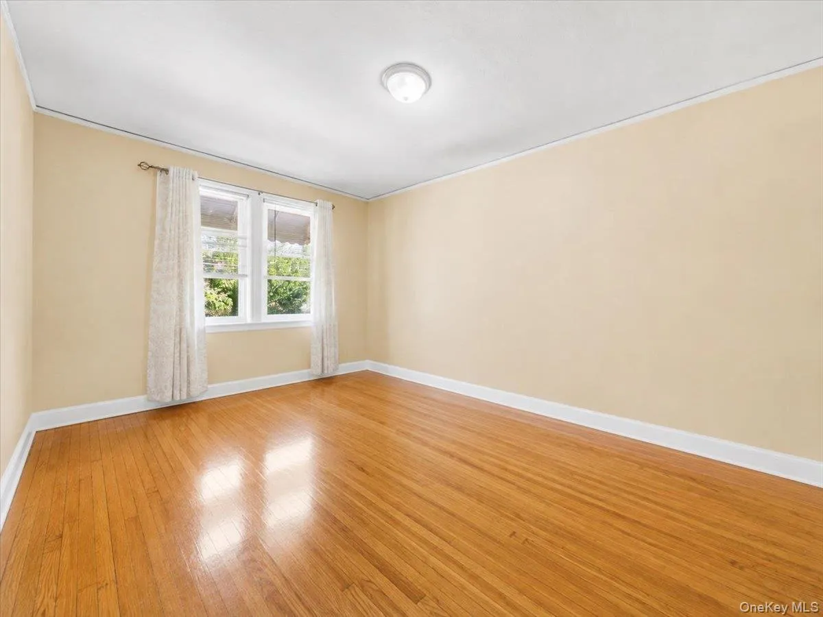 Hardwood flooring, dual windows, white trim, light-colored walls, and a ceiling-mounted light fixture Hardwood flooring, dual windows, white trim, light-colored walls, and a ceiling-mounted light fixture
