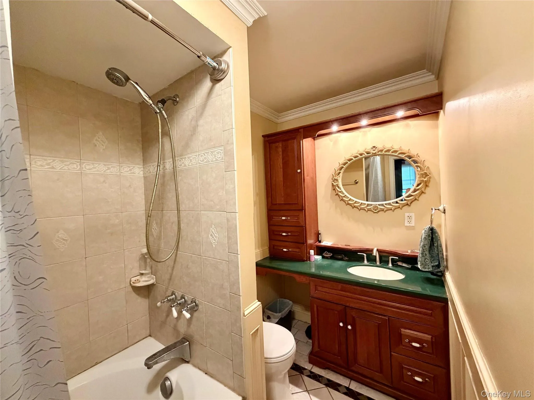Built-in vanity with a green countertop, integrated sink, and an ornamental mirror Built-in vanity with a green countertop, integrated sink, and an ornamental mirror