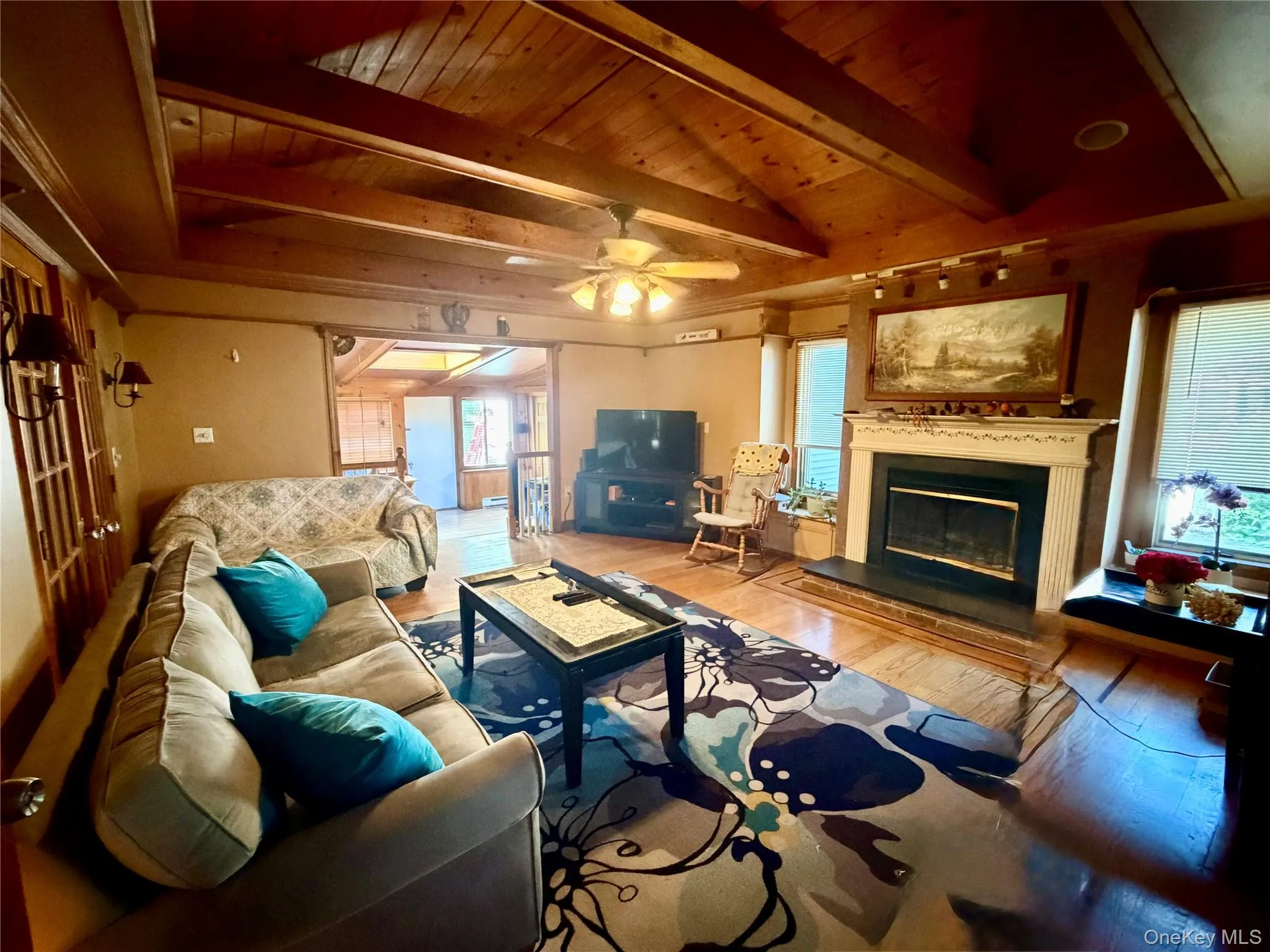 Vaulted wood-paneled ceiling with exposed beams, wood-finish flooring, fireplace with a decorative mantel, ceiling fan, and recessed lighting Vaulted wood-paneled ceiling with exposed beams, wood-finish flooring, fireplace with a decorative mantel, ceiling fan, and recessed lighting