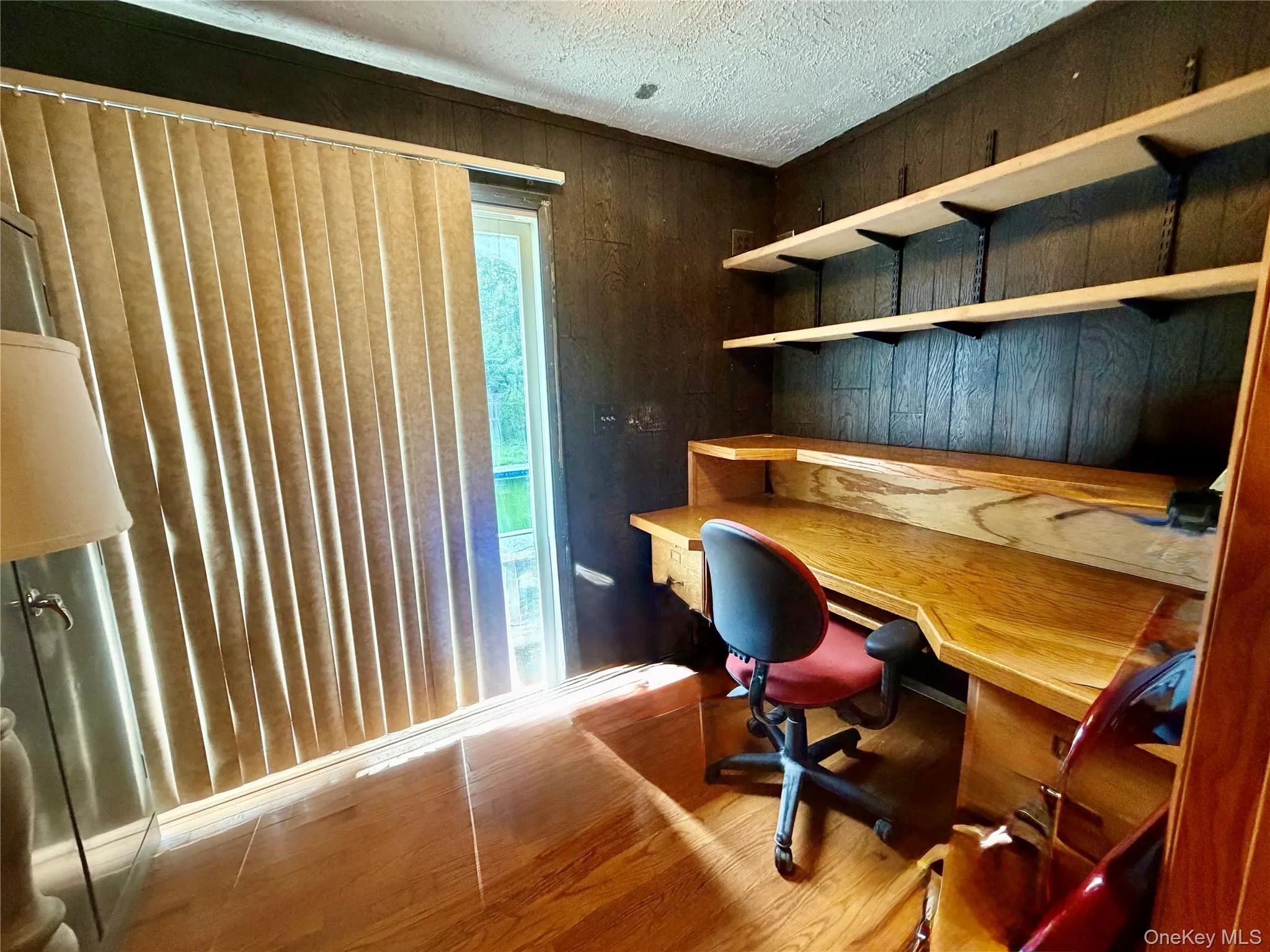 Wood-finish flooring with built-in desk, integrated shelving, and vertical blinds Wood-finish flooring with built-in desk, integrated shelving, and vertical blinds