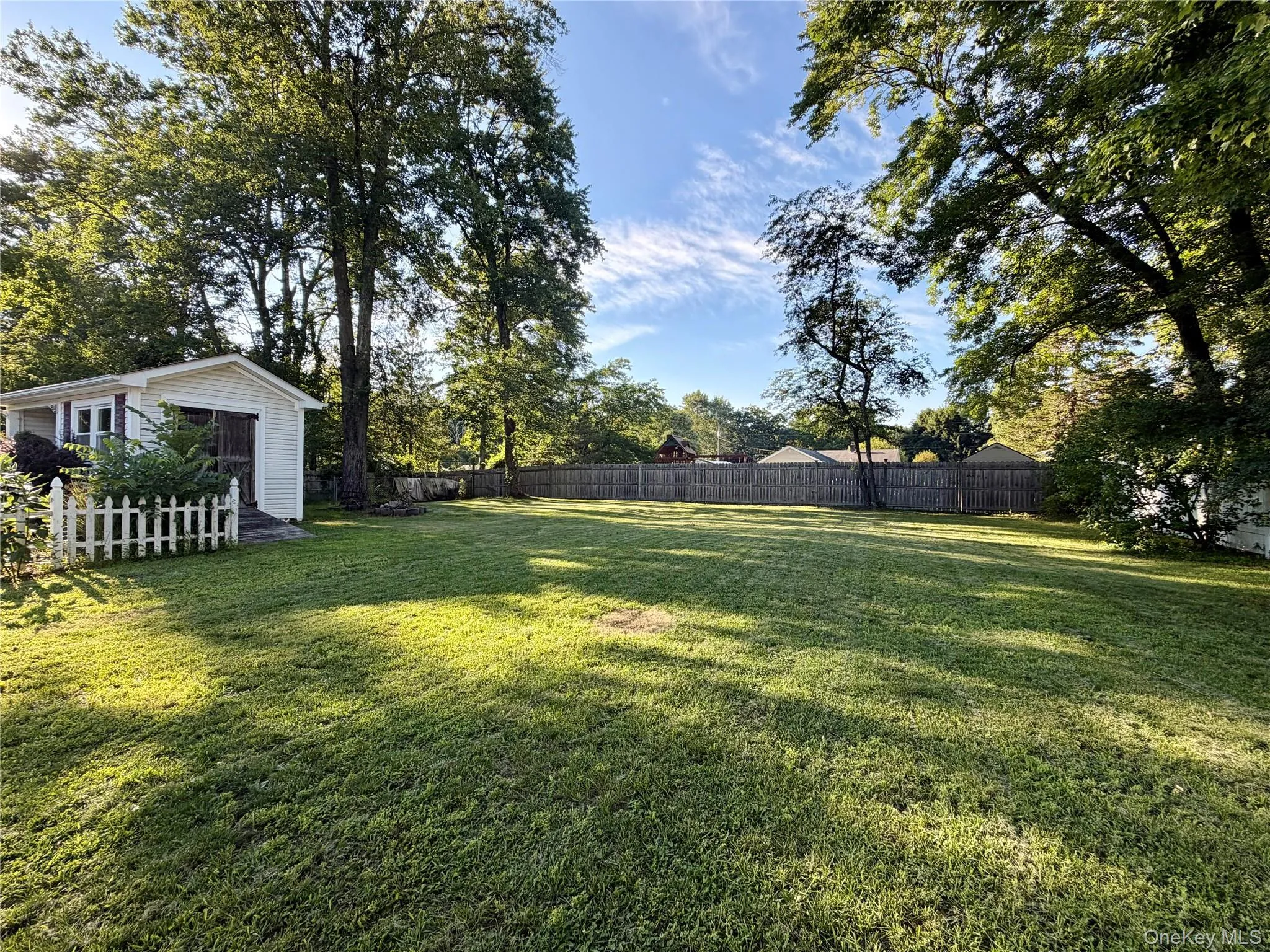 Expansive lawn with mature trees, surrounded by a wood privacy fence Expansive lawn with mature trees, surrounded by a wood privacy fence