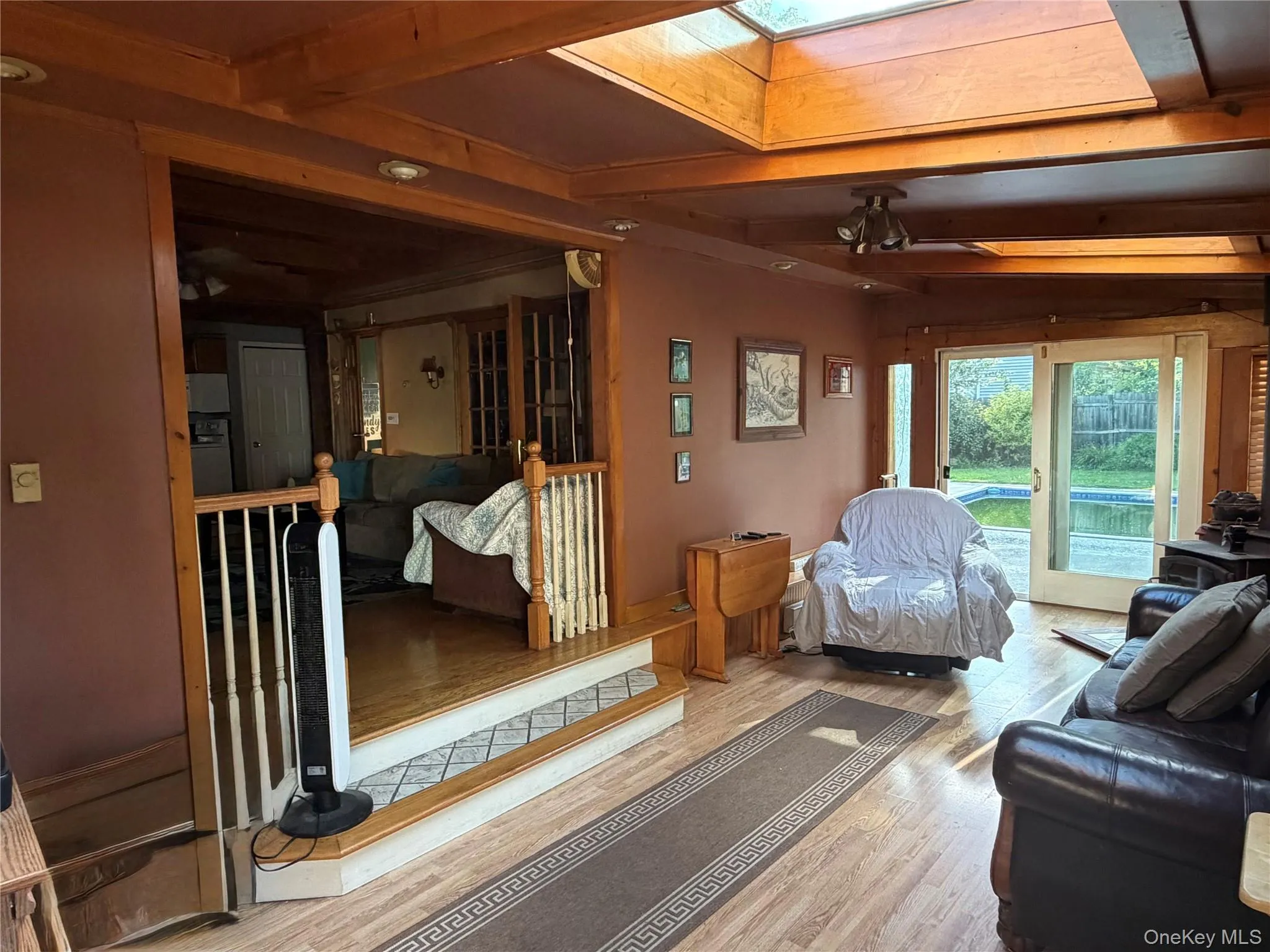 Wood-finish flooring, wood paneling, wood blinds, recessed lighting, and a stairway with wood railing Wood-finish flooring, wood paneling, wood blinds, recessed lighting, and a stairway with wood railing