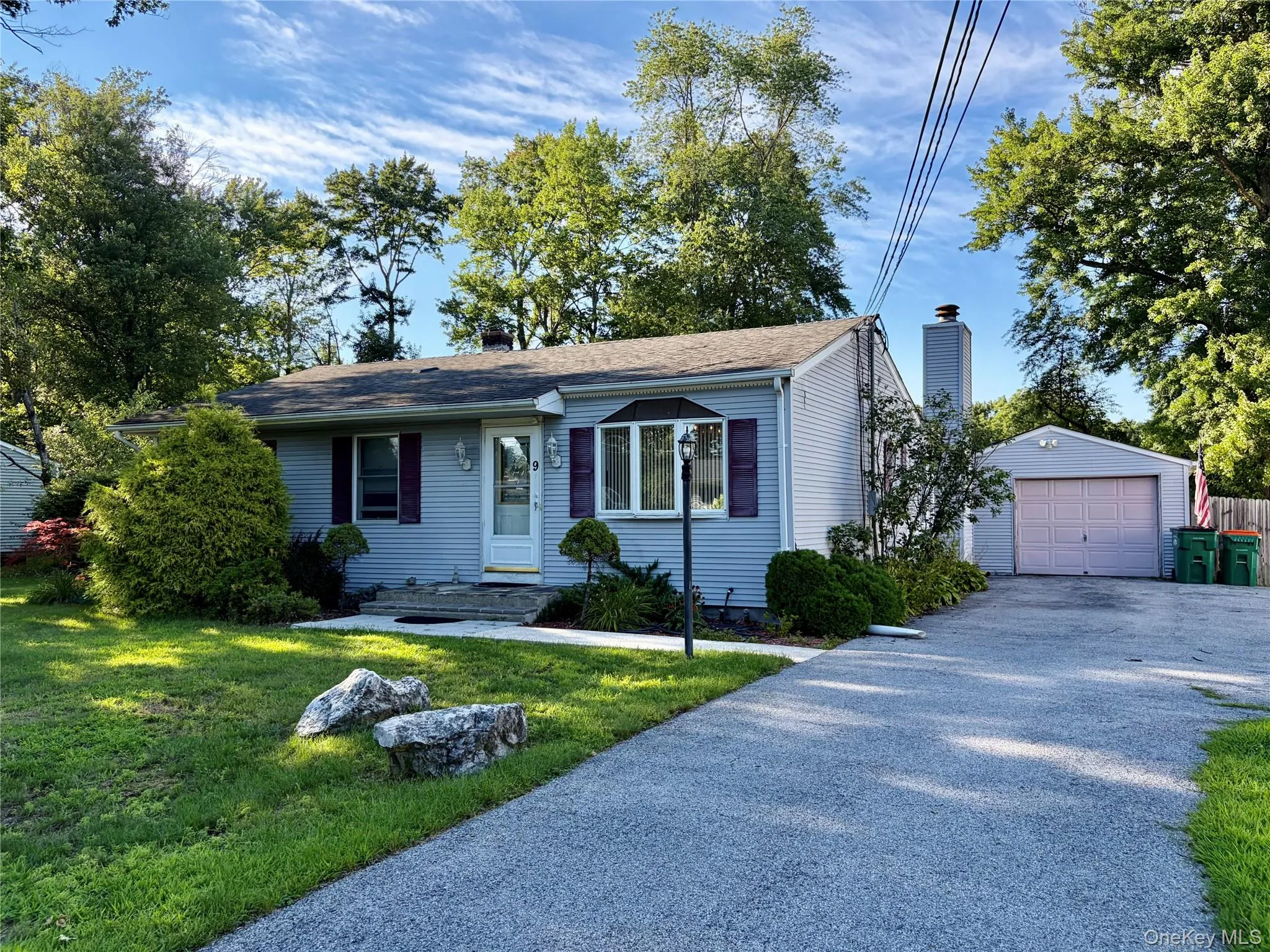 Siding exterior with a covered entry, established landscaping, and a driveway leading to an attached garage Siding exterior with a covered entry, established landscaping, and a driveway leading to an attached garage