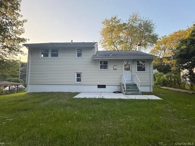 Back of property with entry steps, a yard, a patio area, and a chimney Back of property with entry steps, a yard, a patio area, and a chimney